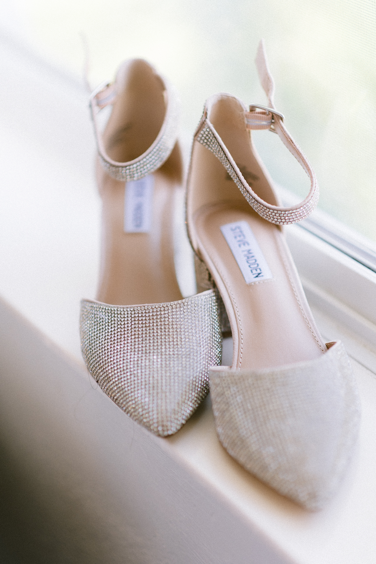 A pair of elegant, rhinestone-studded high heels displayed on a window sill