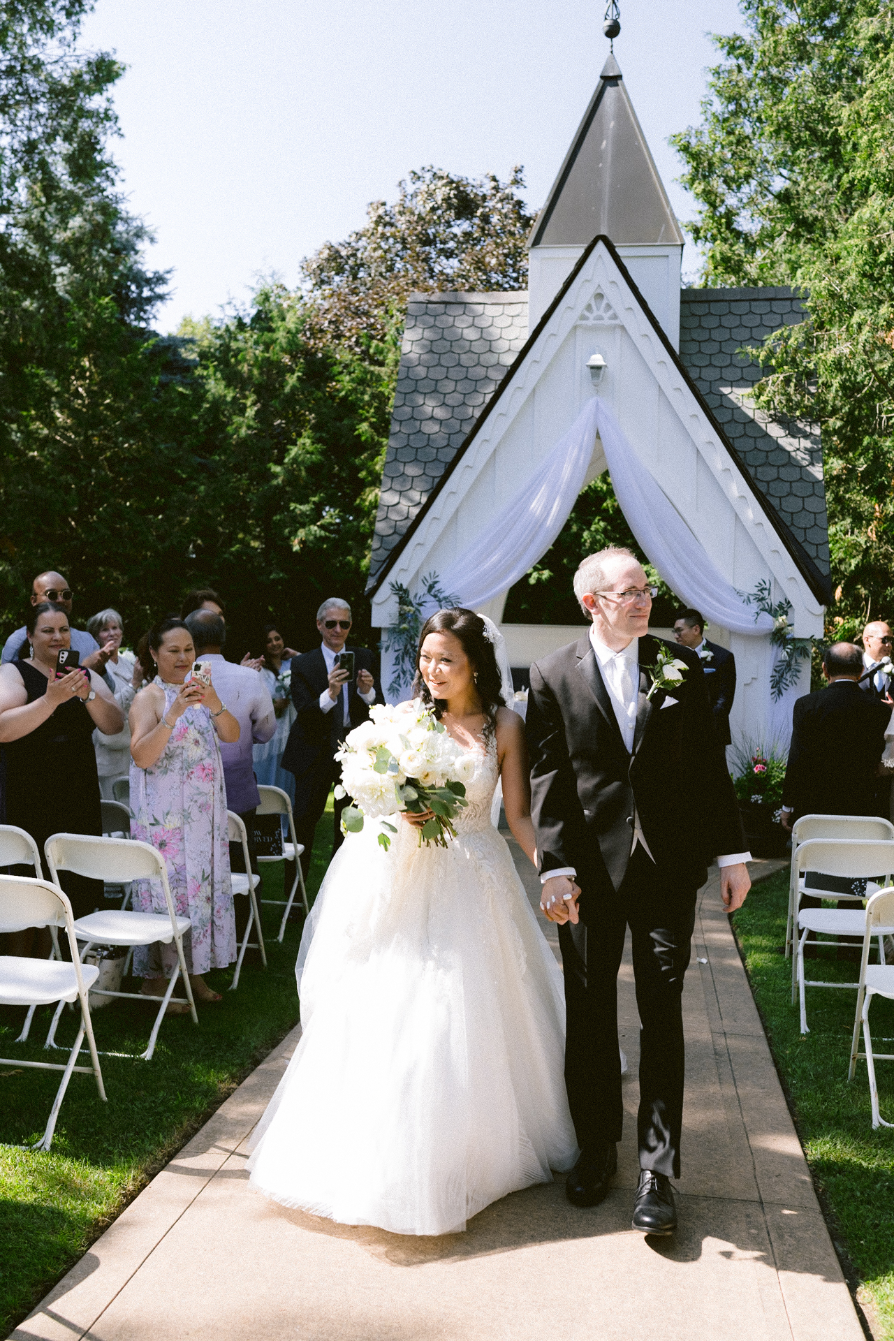 Bride and father walking down the aisle at an outdoor wedding ceremony.