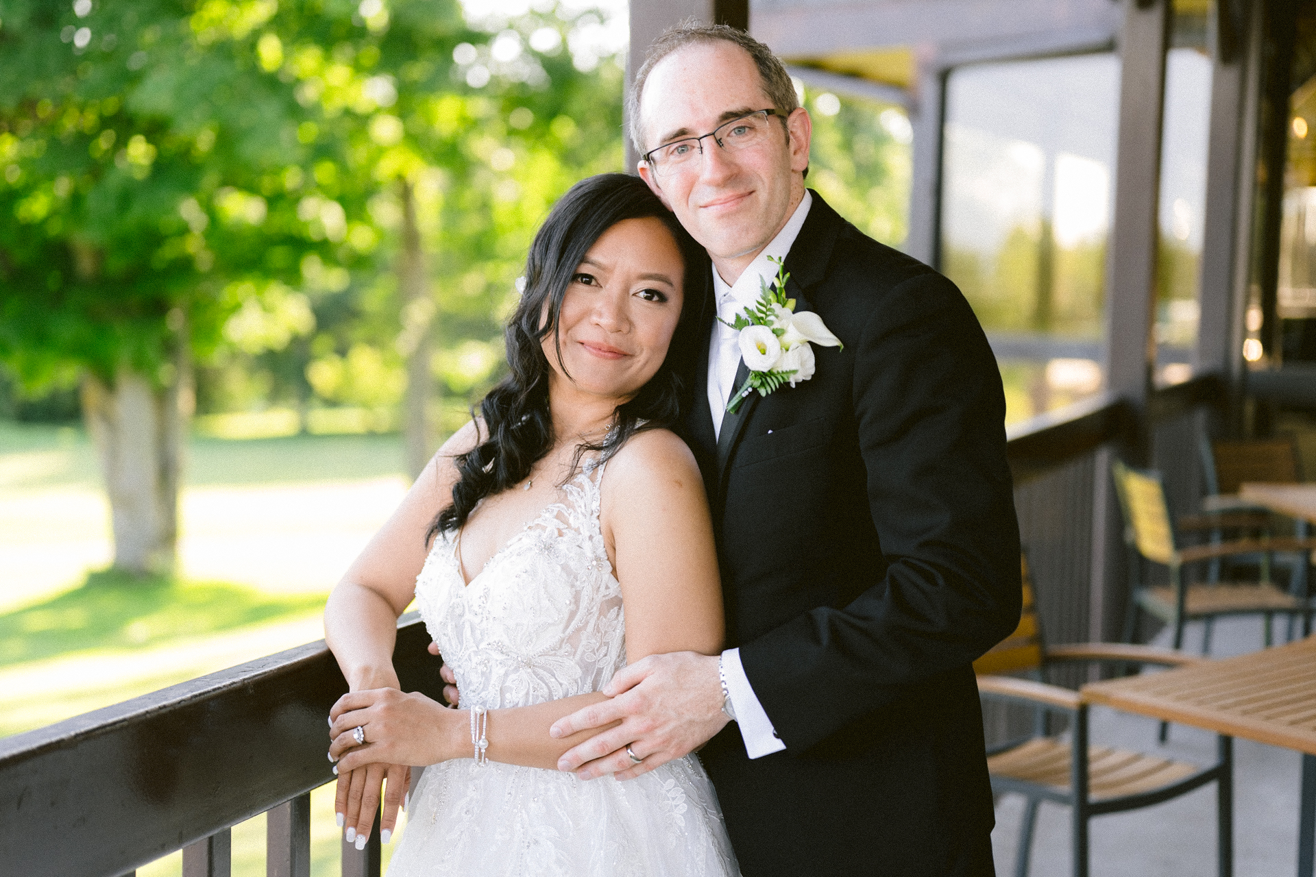 A bride and groom smiling together outdoors on their wedding day.