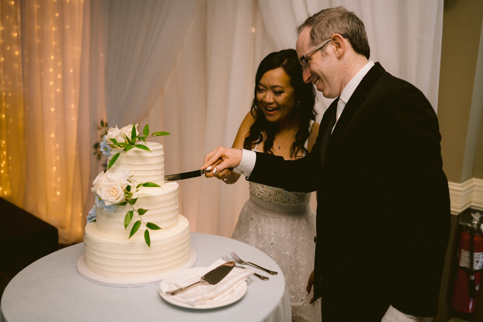 Bride watches as groom cuts the wedding cake.