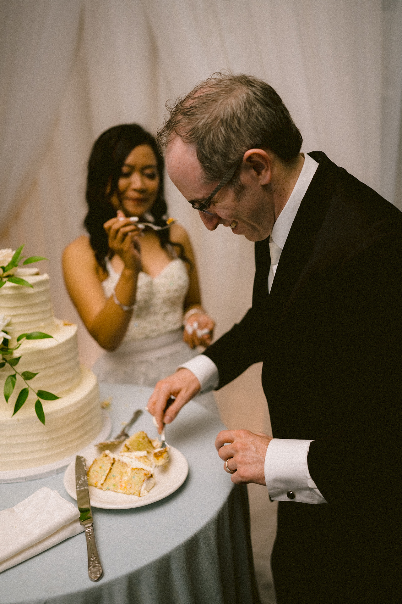 Bride watches as groom cuts the wedding cake.