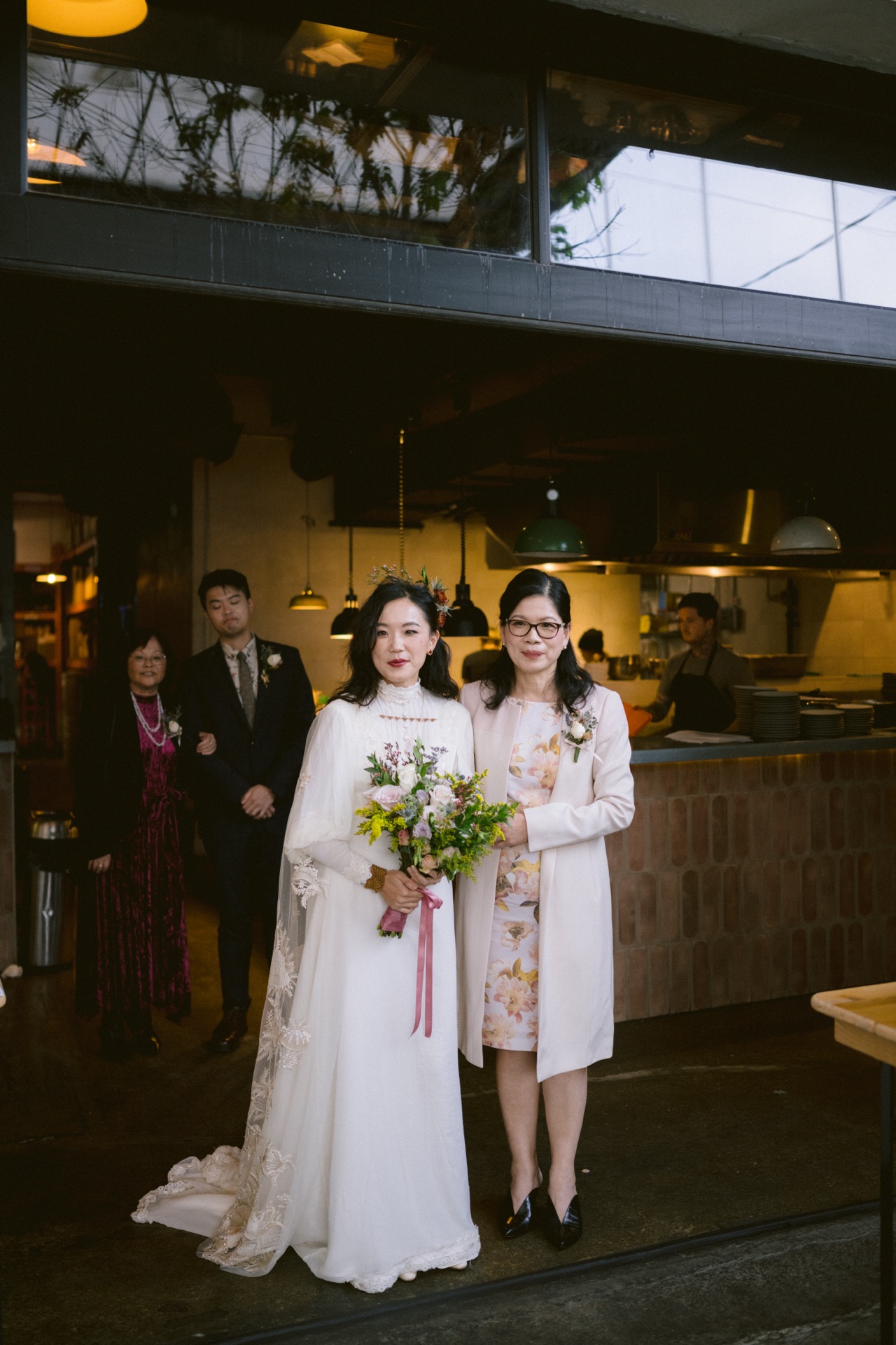 Bride holding a bouquet, with guests in the background.