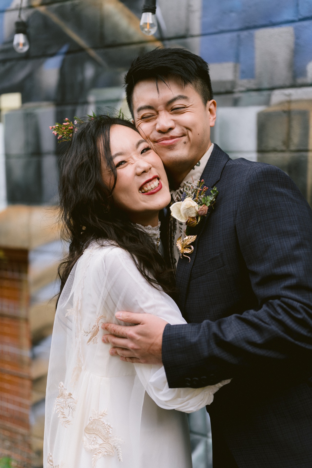 Bride and groom cuddle each other in front of a mural after their micro-wedding ceremony.