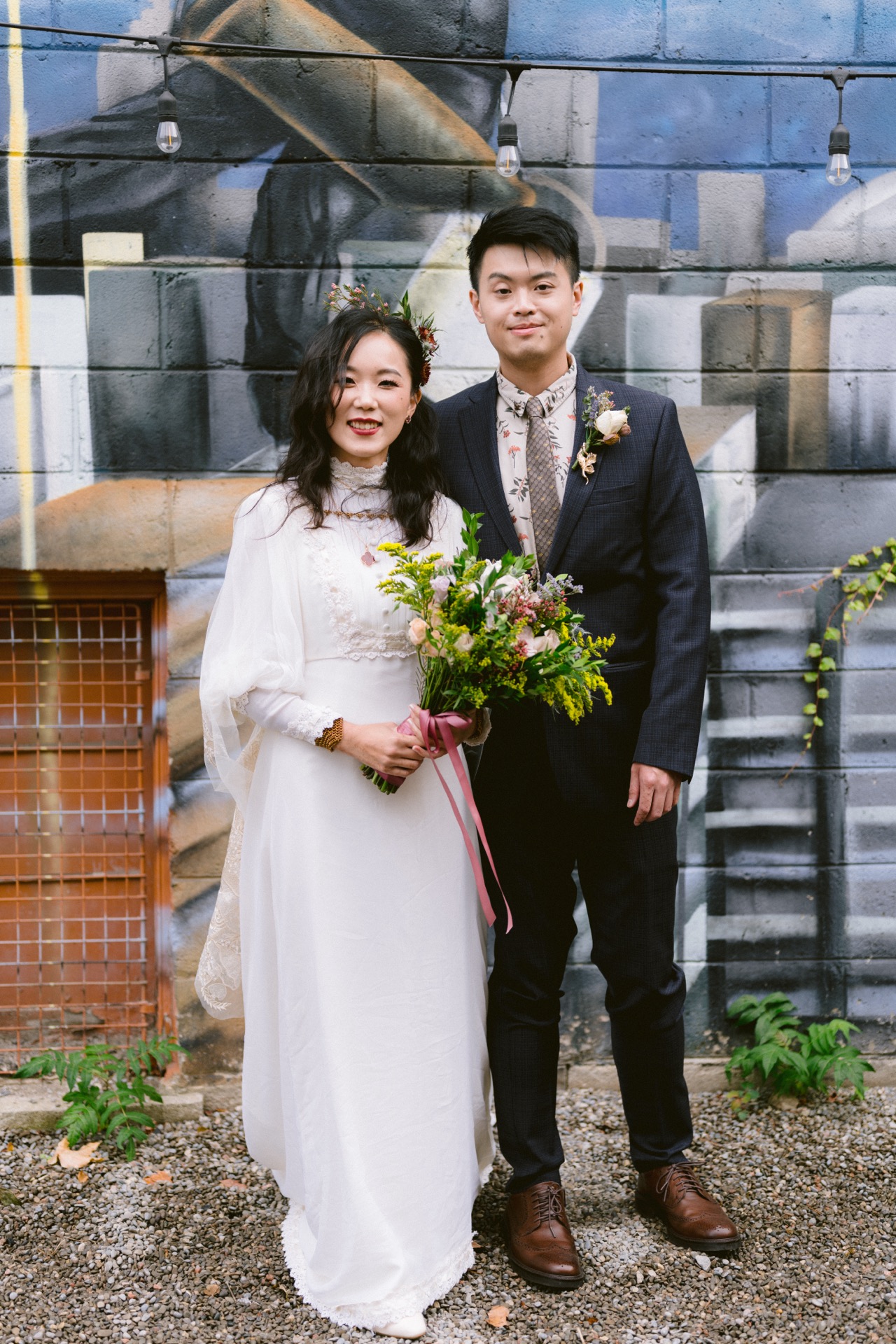 Bride and groom posing in front of a mural for their micro-wedding portrait.