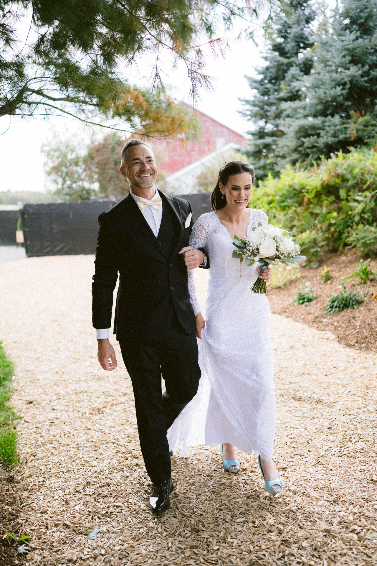 A bride holding her brother in wedding attire walking hand in hand down the aisle.