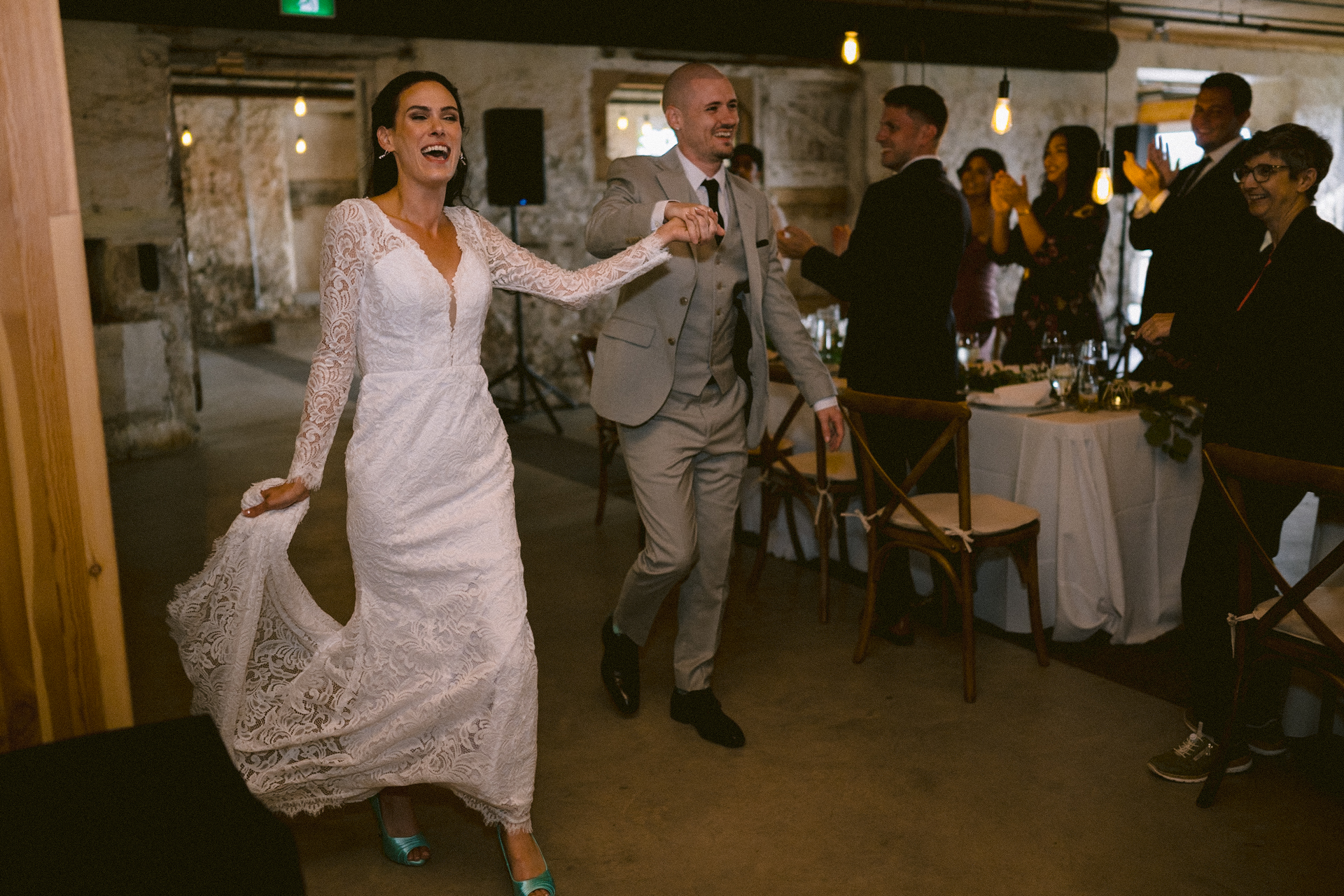 Bride and groom joyfully grand entrance to their wedding reception with all the guests standing up to welcome them.