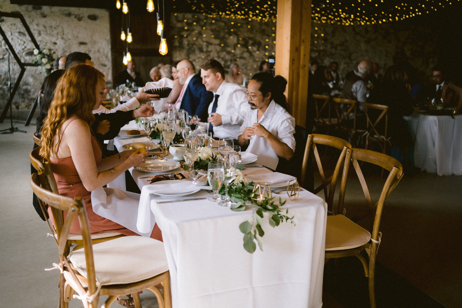 Guests seated and engaged in conversation at a banquet table adorned with simple floral decorations and elegant tableware