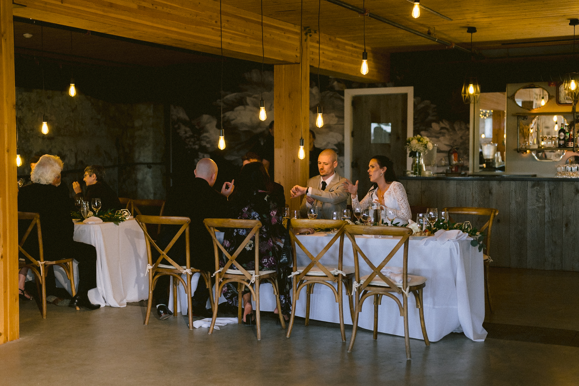 Guests seated and engaged in conversation at a banquet table adorned with simple floral decorations and elegant tableware