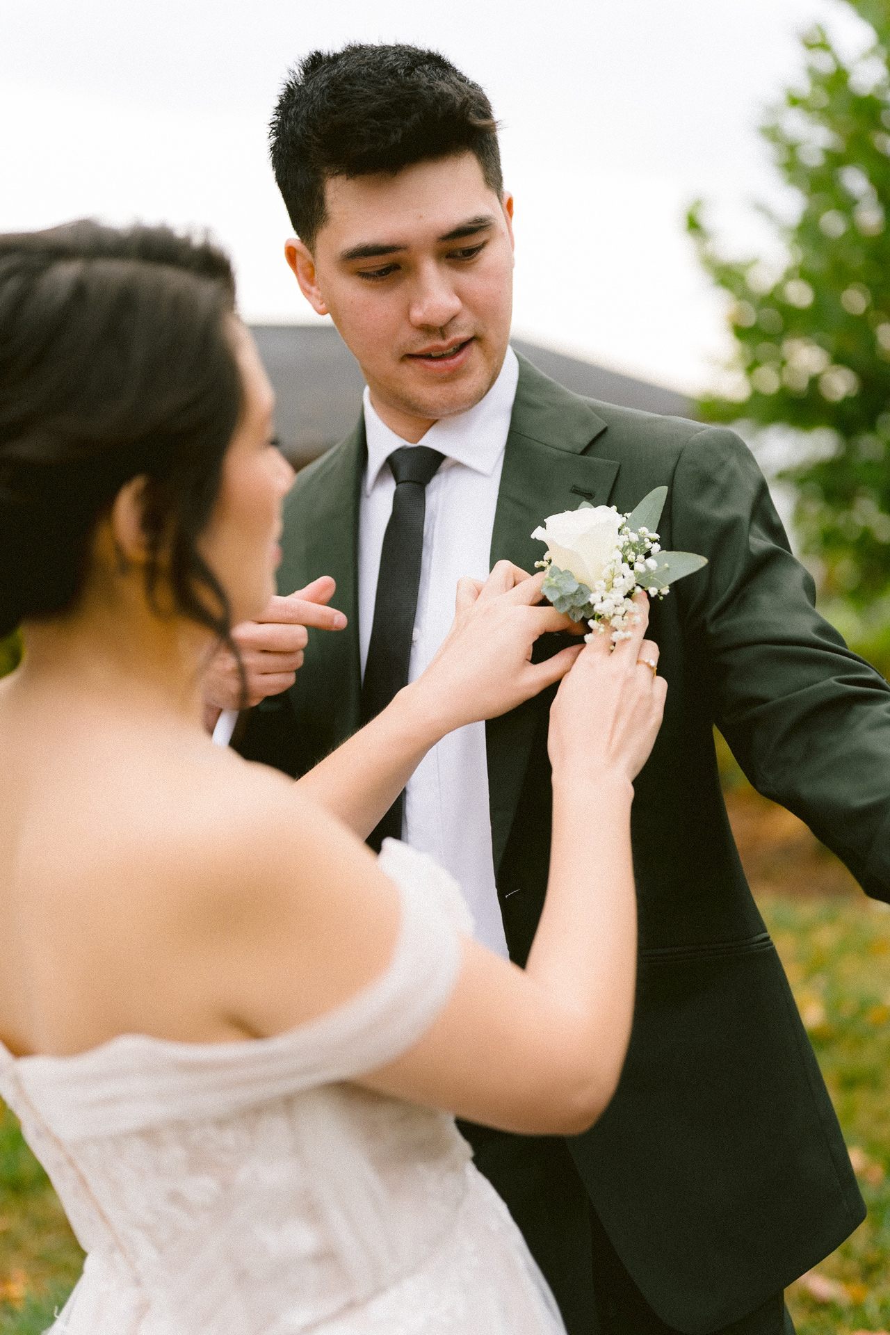 A man in a suit adjusting a white boutonnière.