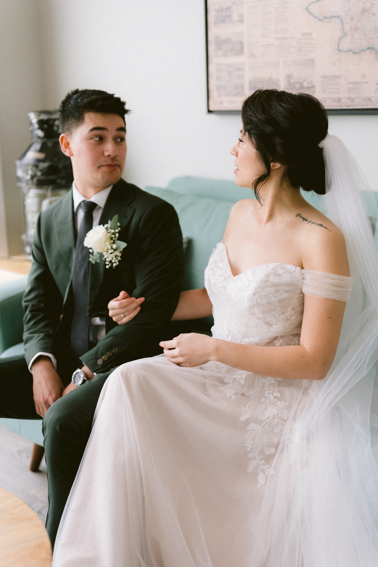 A bride and groom sitting on a sofa, reading heartfelt notes, with the groom appearing to wipe a tear and the bride smiling