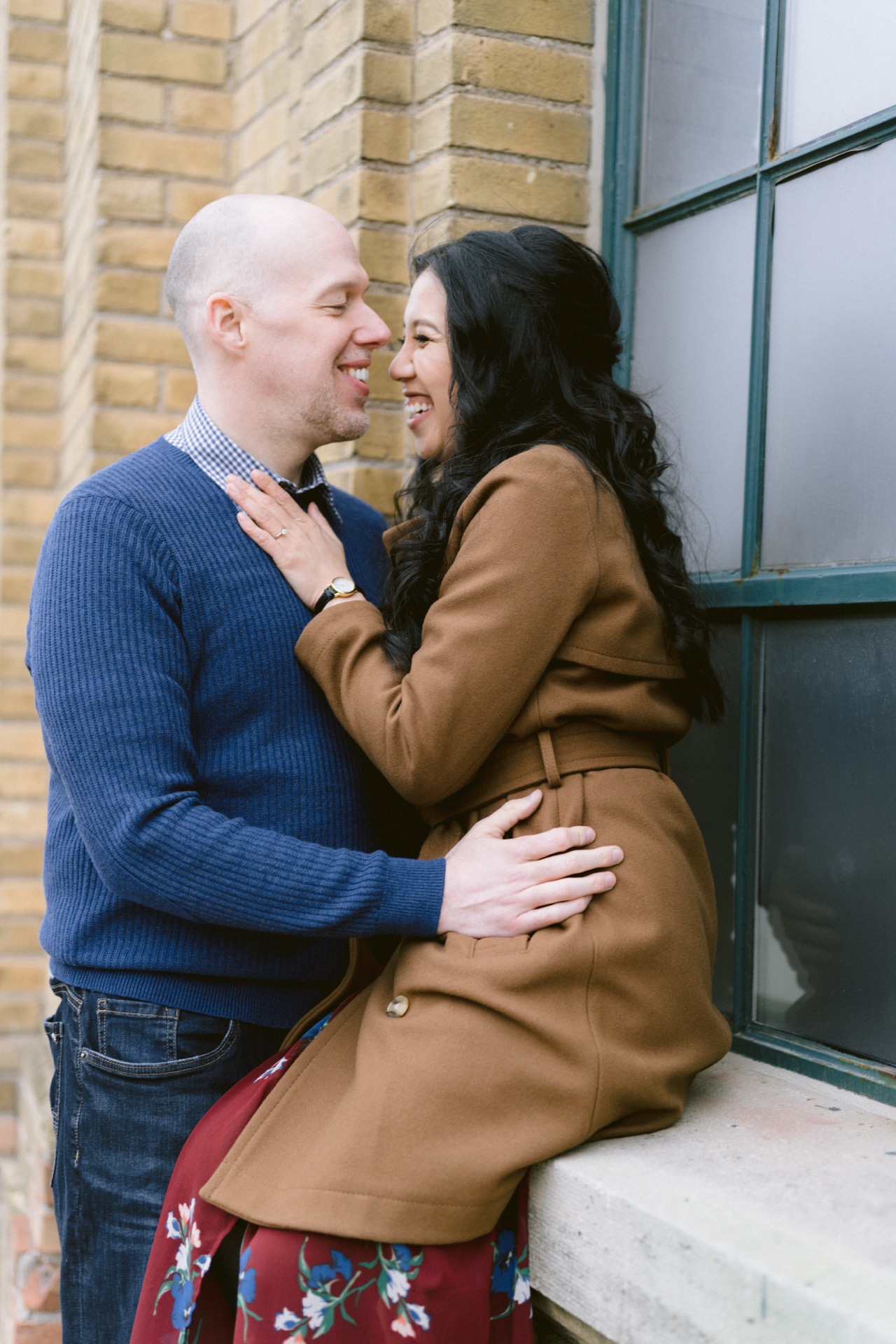 A man and a woman standing side by side in front of a corrugated metal wall.