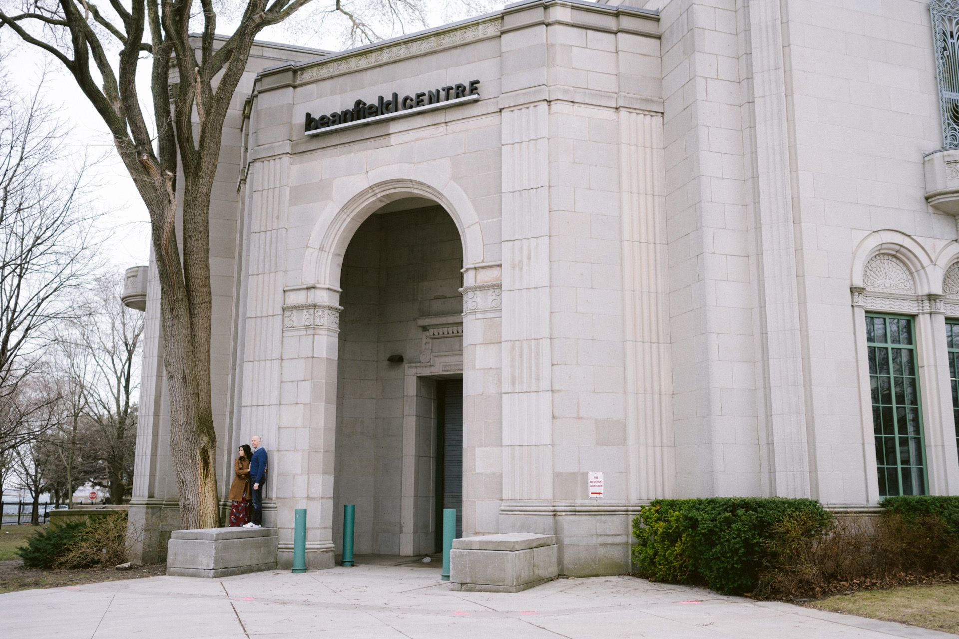 Two individuals stand by the entrance of the hart house theatre.