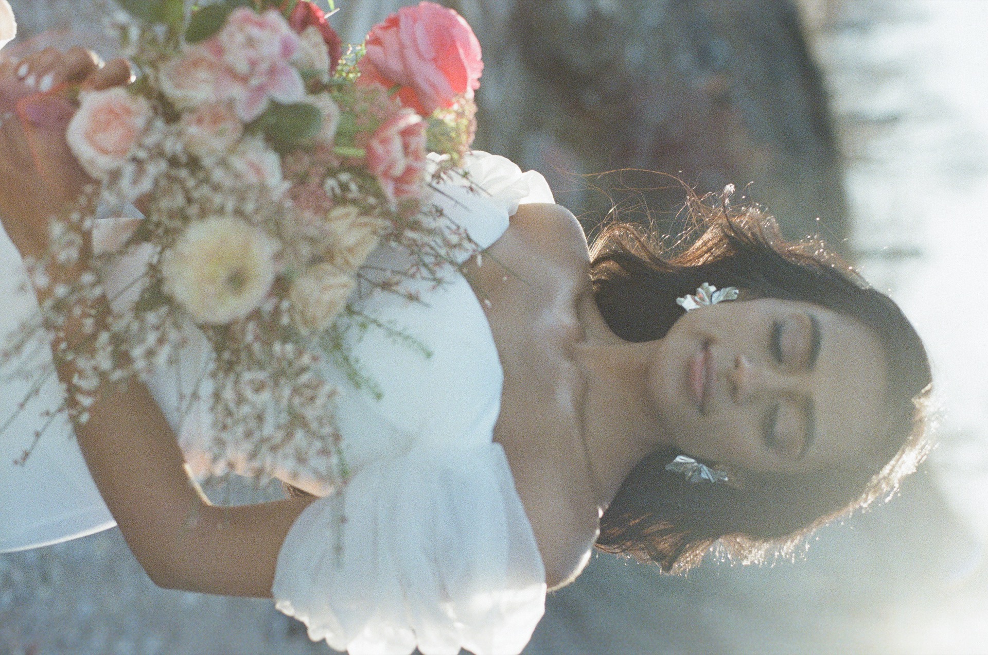 Bride closing her eyes, holding a bouquet with both hands while waiting for the first look.