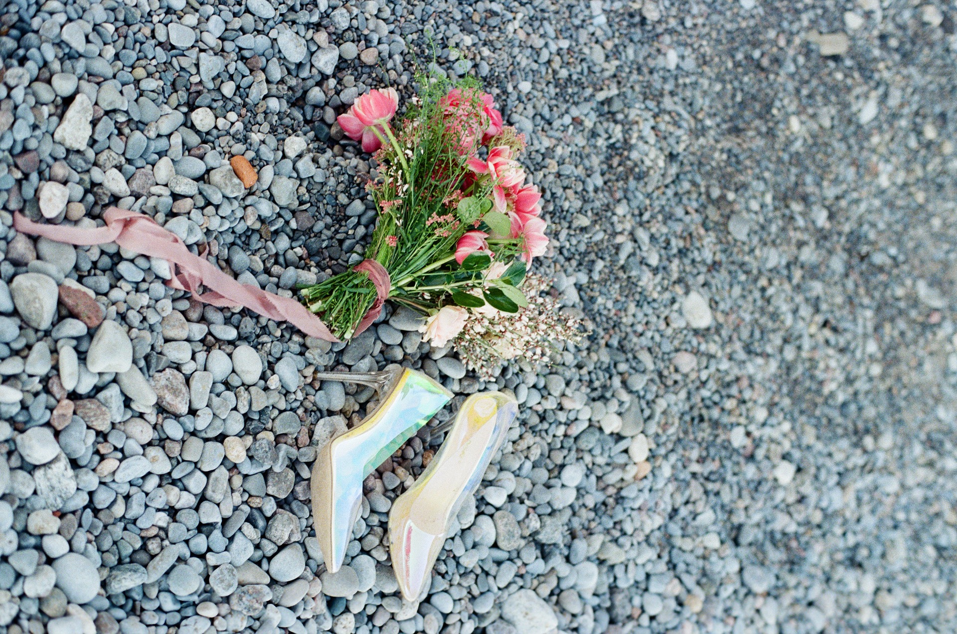 The matching color of a wedding bouquet with a wedding shoe displayed by the lake.