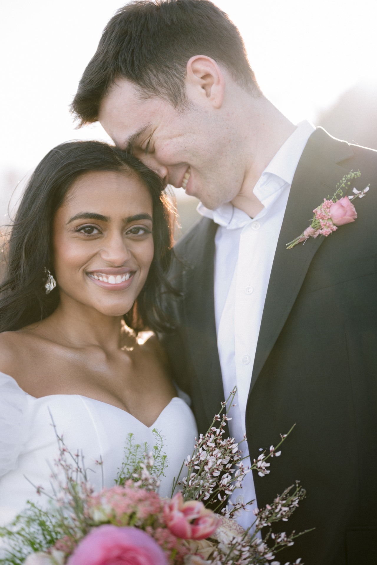 Groom kissed the forehead of a bride when the bride smile gently toward the camera.