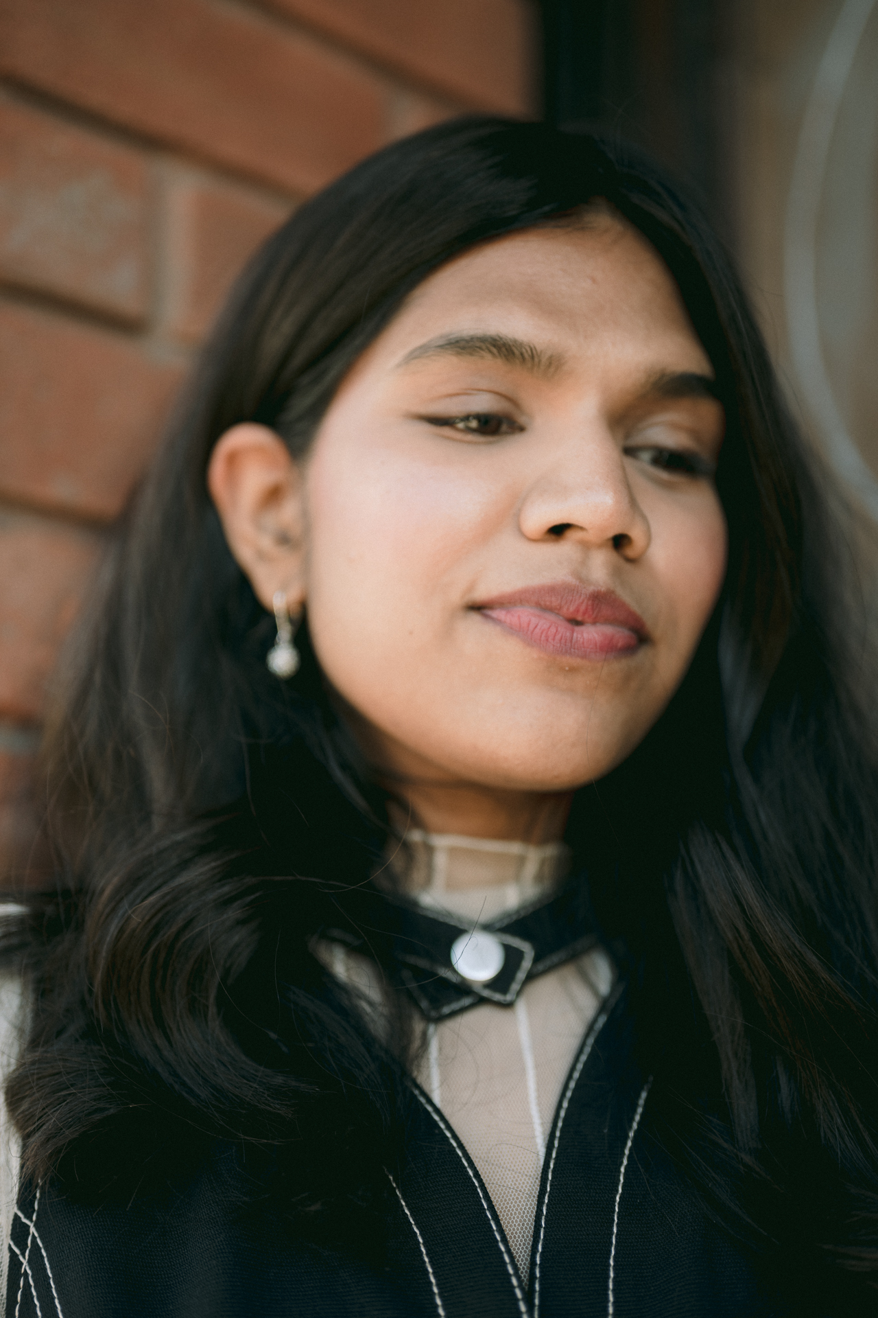 A close up of a girl with a pearl earring happily posing for her engagement photoshoot.