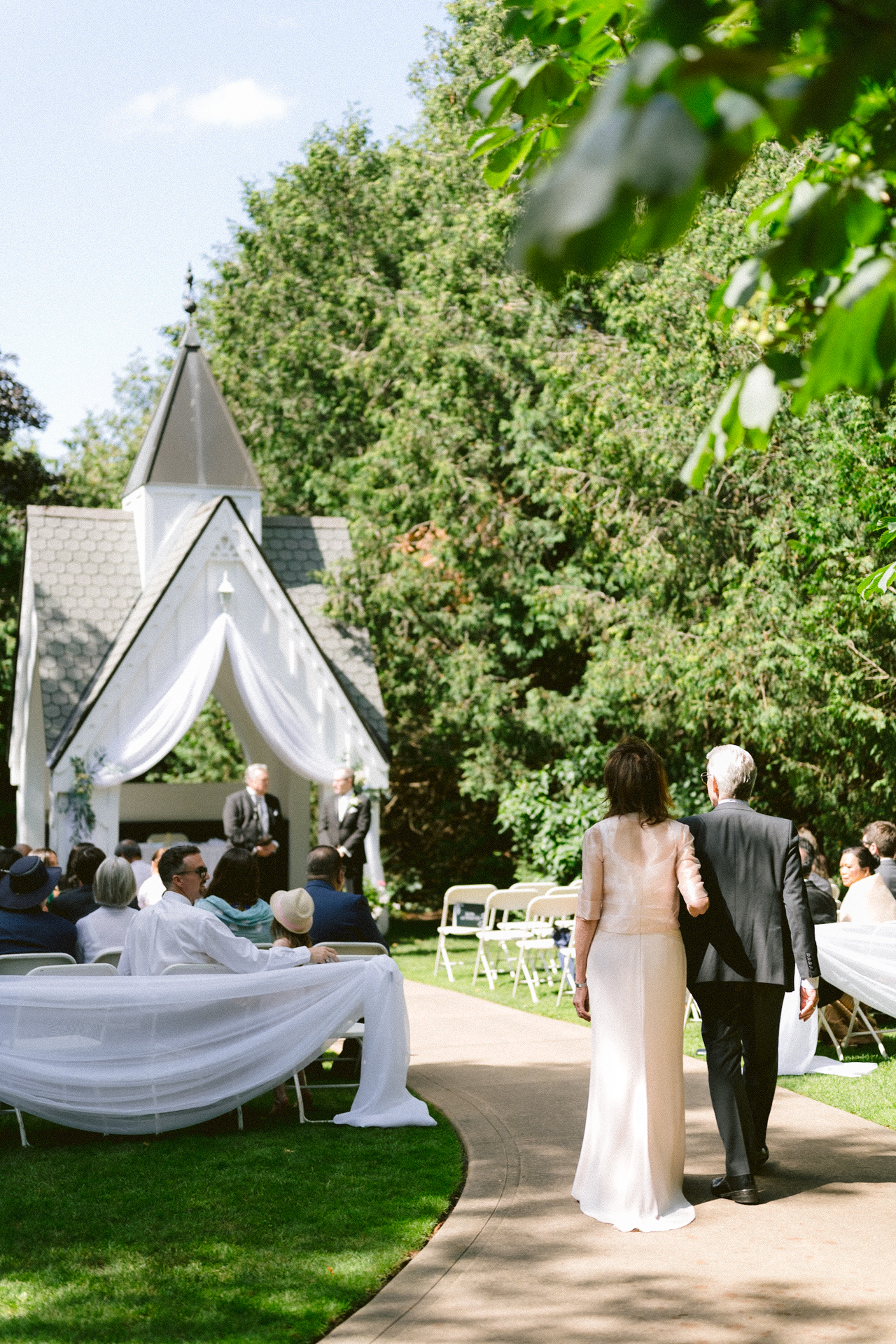 A couple walking down the aisle at an outdoor wedding ceremony.
