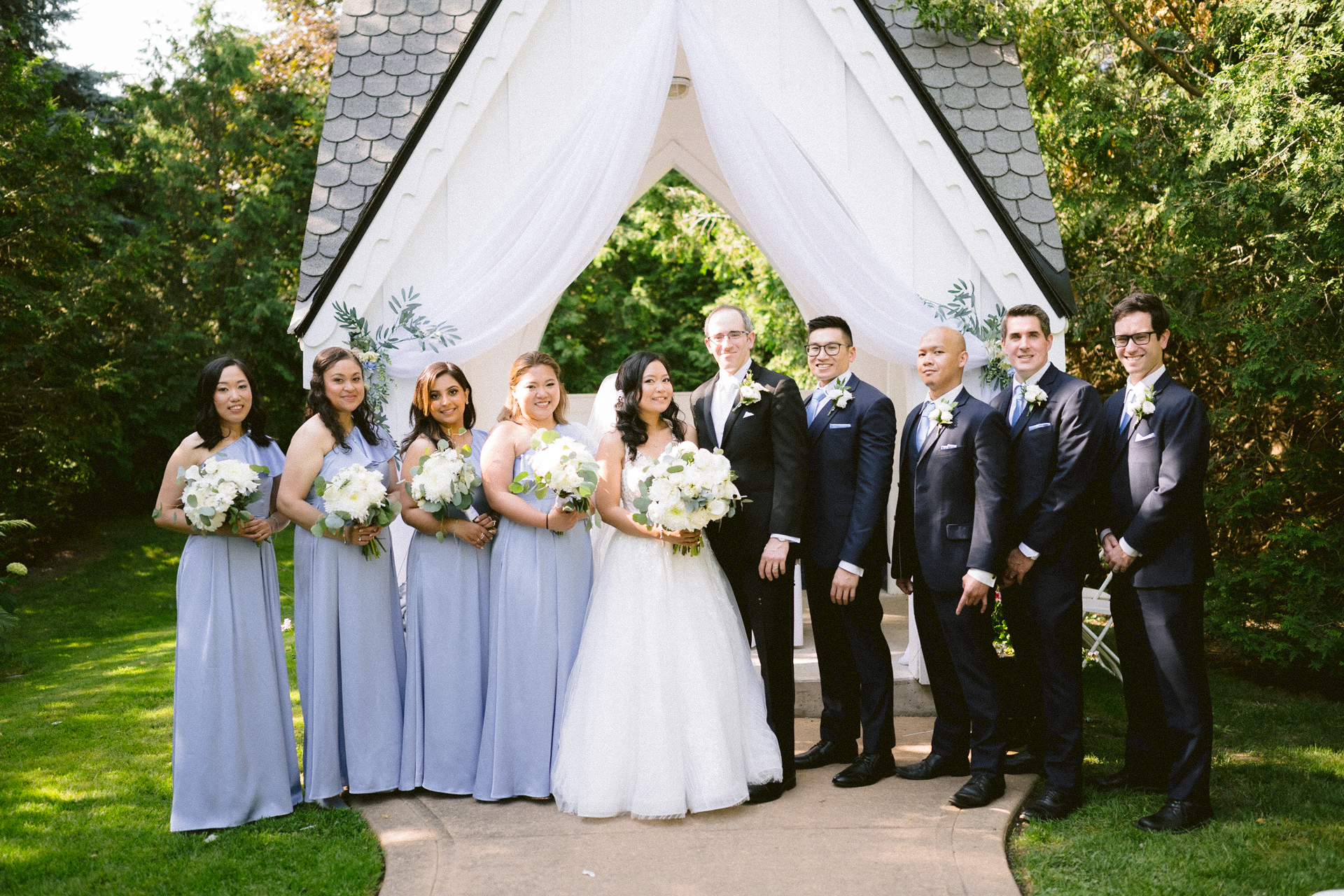 A bridal party posing for a photograph at an outdoor wedding ceremony.