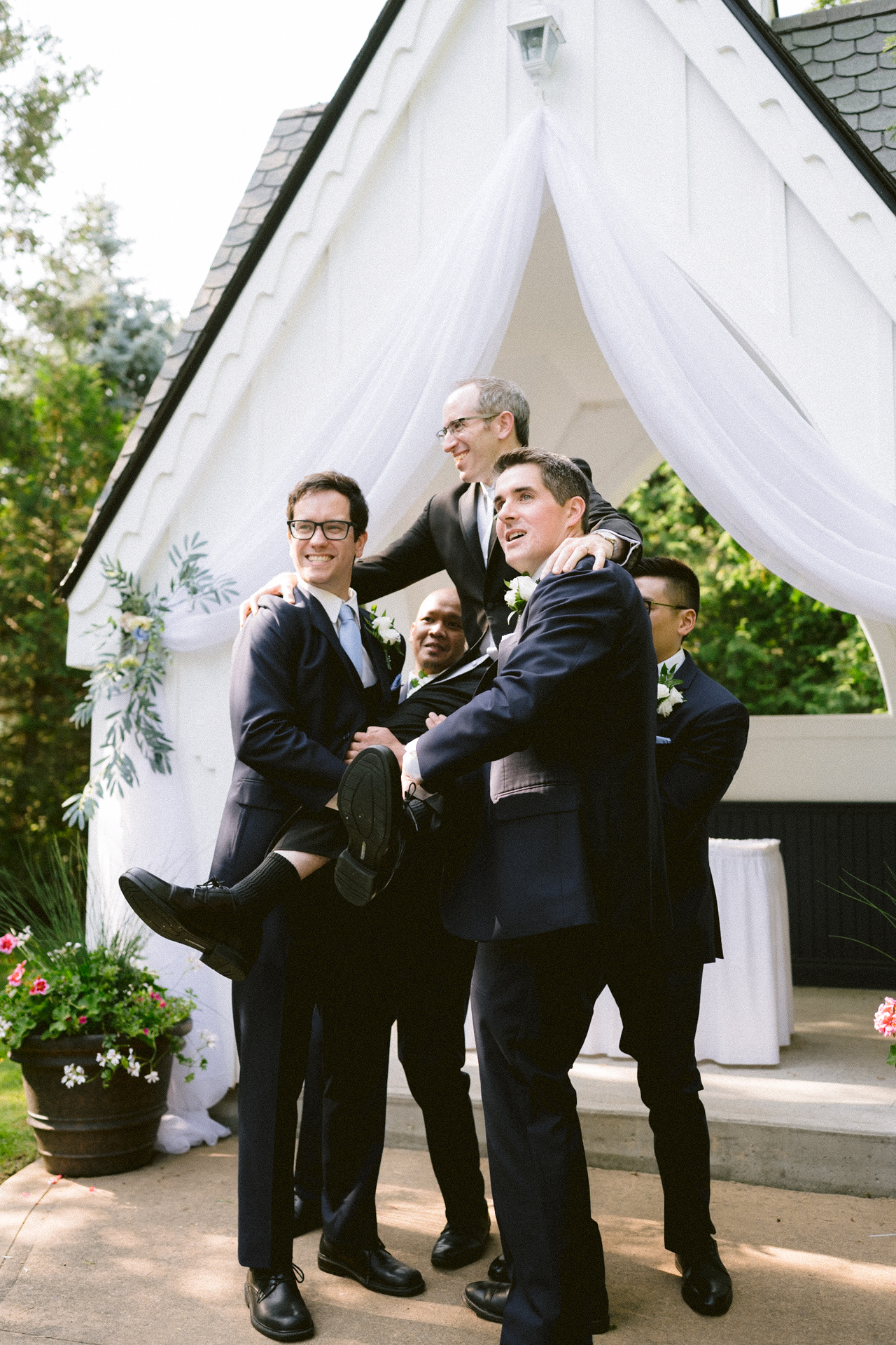 Groomsmen lifting the groom for a playful photo at a wedding ceremony.