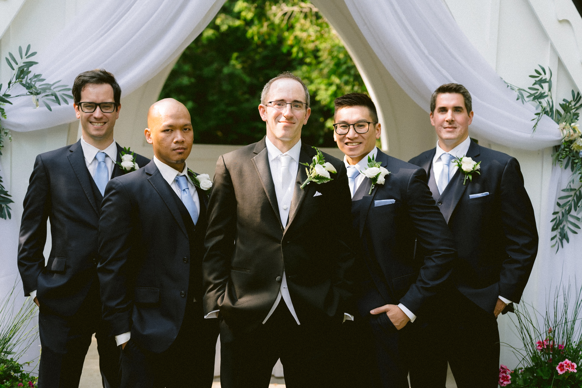 Groom and groomsmen standing together in formal attire at a wedding ceremony.
