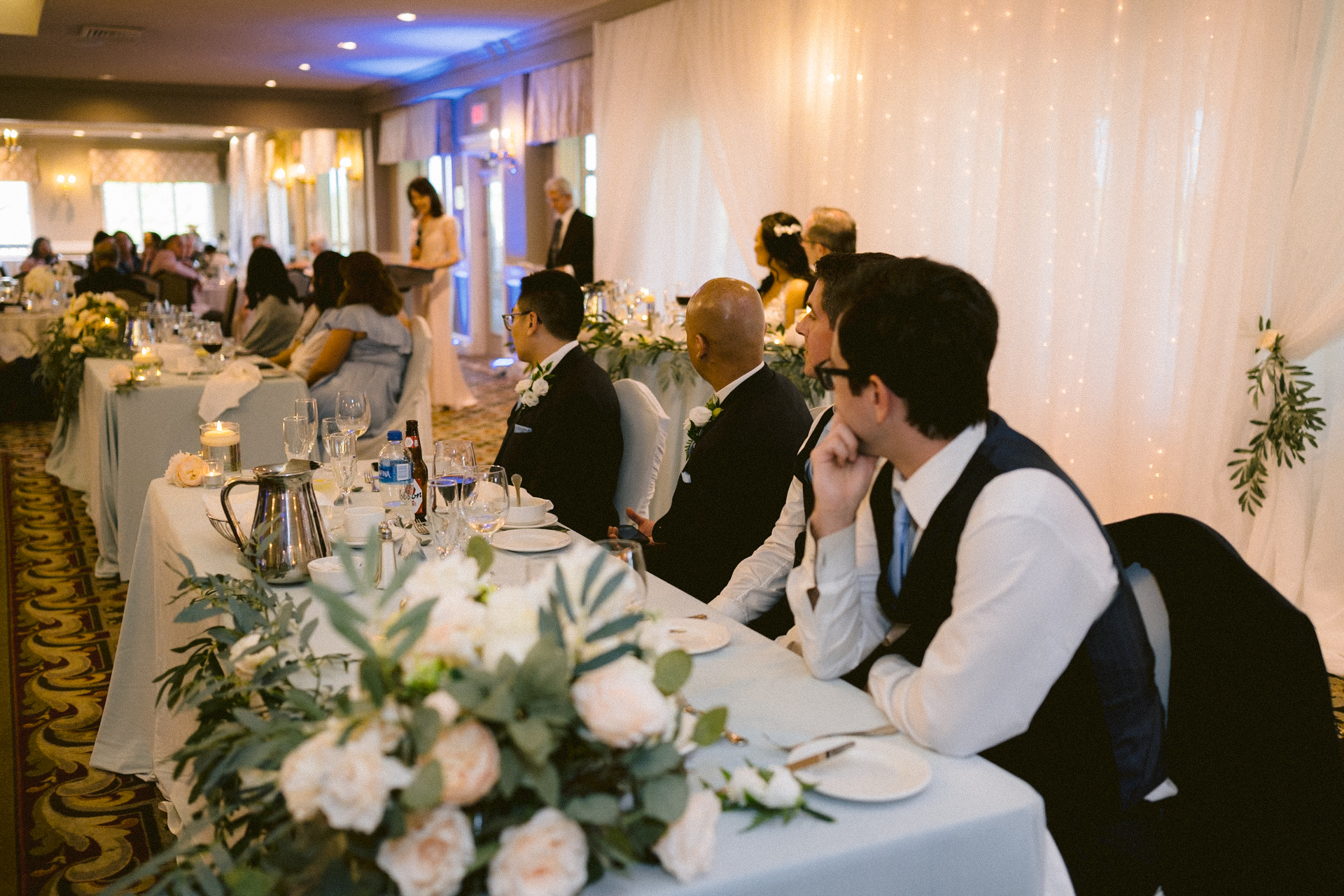 Guests seated at a decorated head table during a wedding reception.