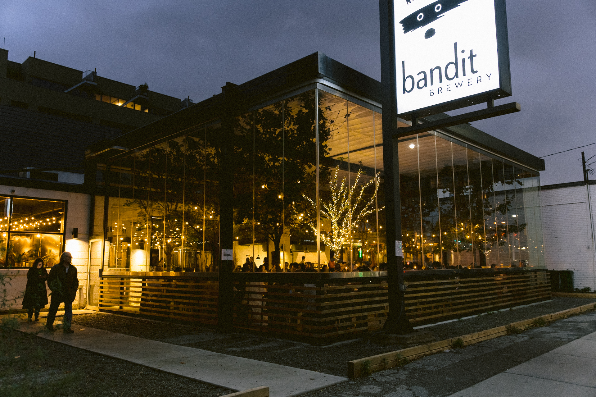 Twilight view of bandit brewery with outdoor lighting and patrons inside.