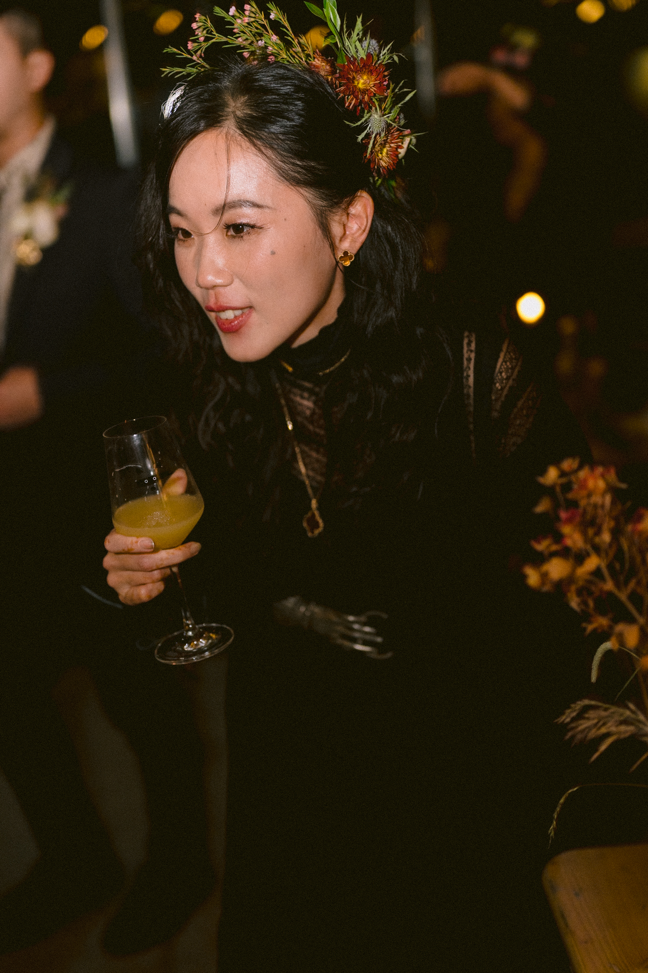 Woman with a floral headpiece holding a glass at an event.