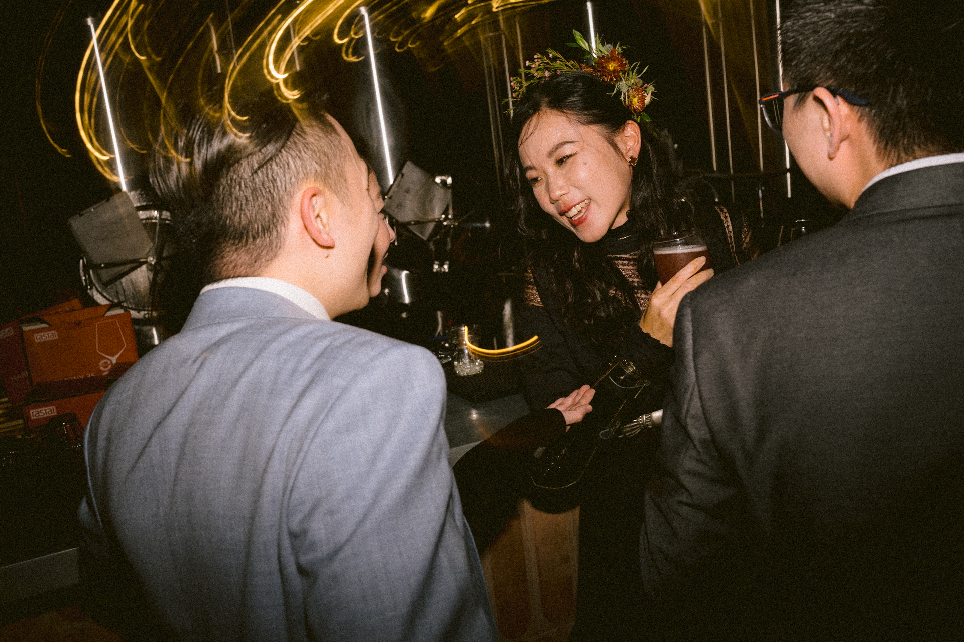 Bride laughing during a conversation with two men at an evening event.