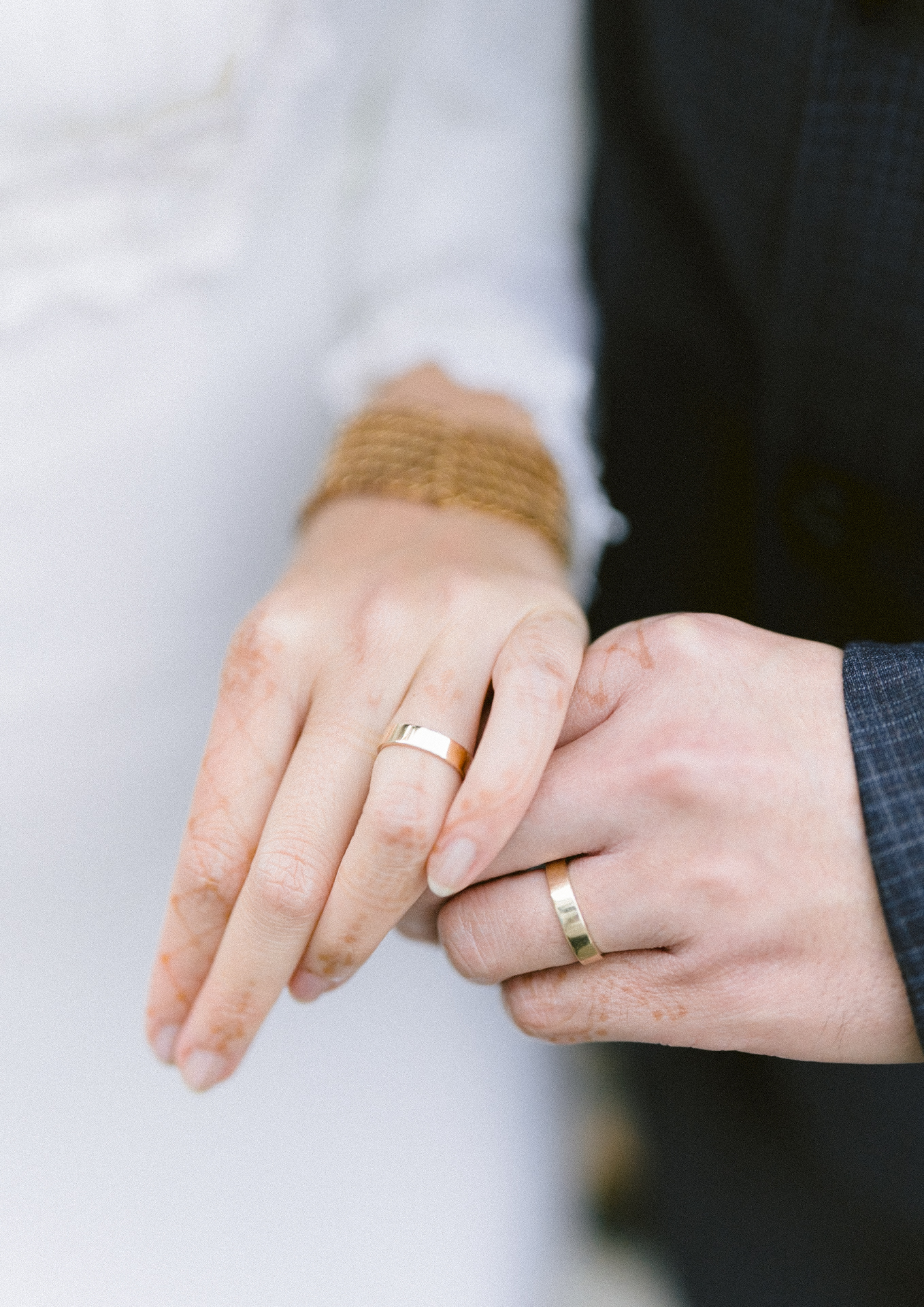 A close-up of a couple's hands showcasing their wedding rings.