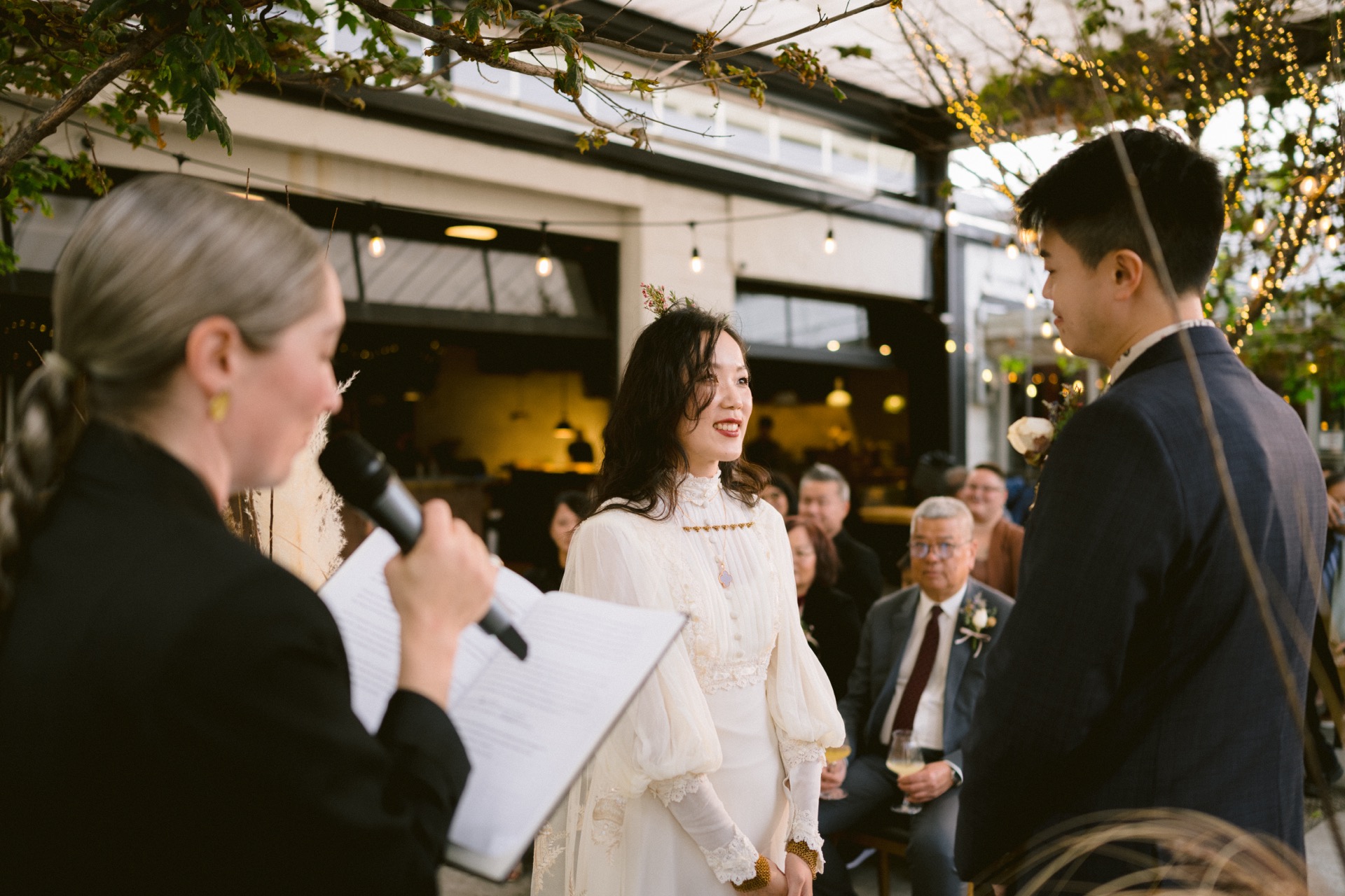 A bride and groom exchange vows outdoors with an officiant leading the ceremony for their micro-wedding.