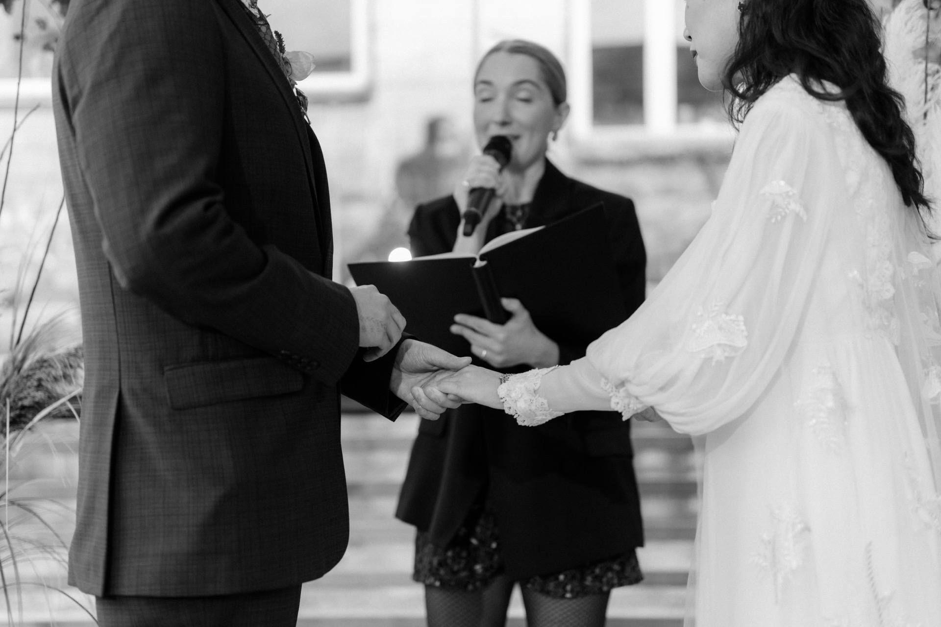 A wedding officiant speaking as a couple holds hands during a ceremony