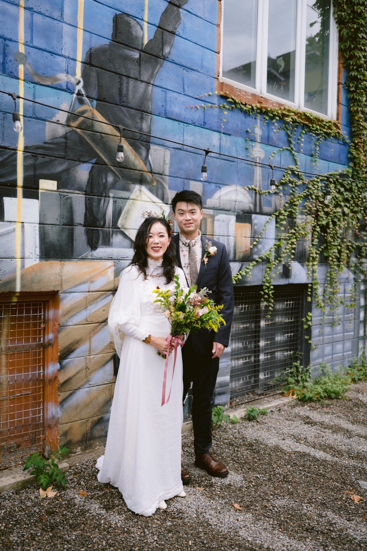 Bride and groom posing in front of a mural for their micro-wedding.
