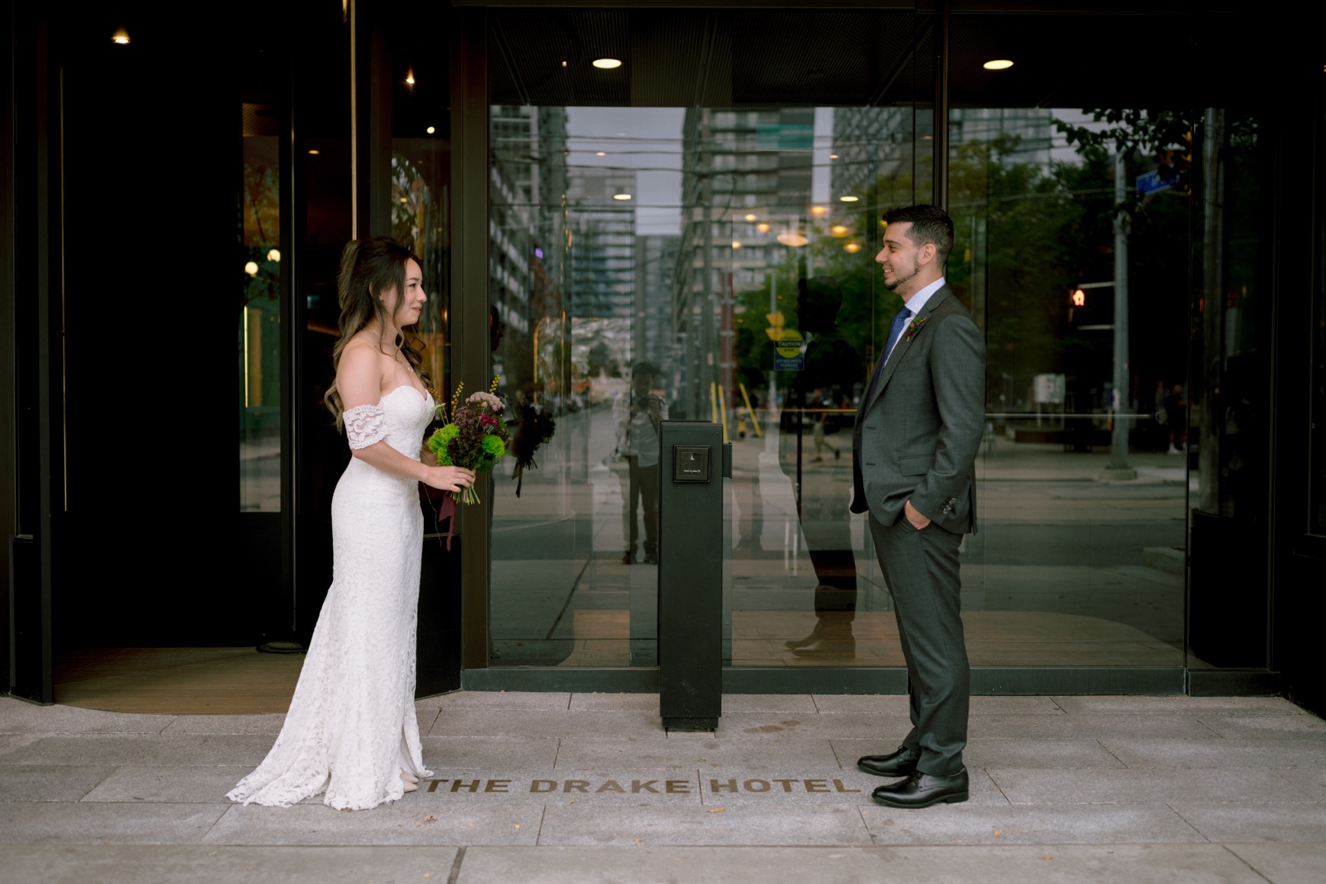 The couple laughing in front of The Drake Hotel for their wedding portrait. 