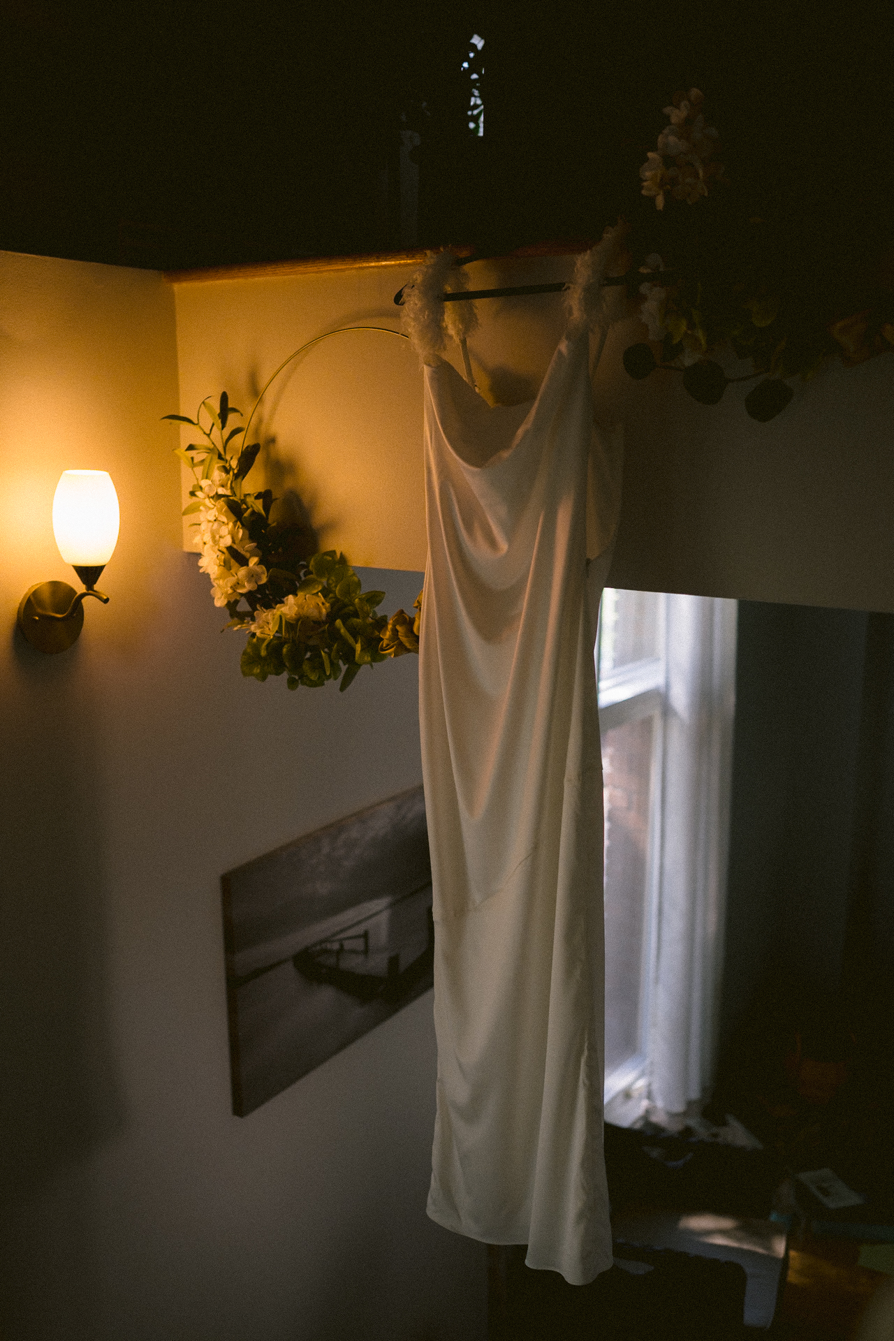 A wedding dress hanging, illuminated by warm light with a window in the background