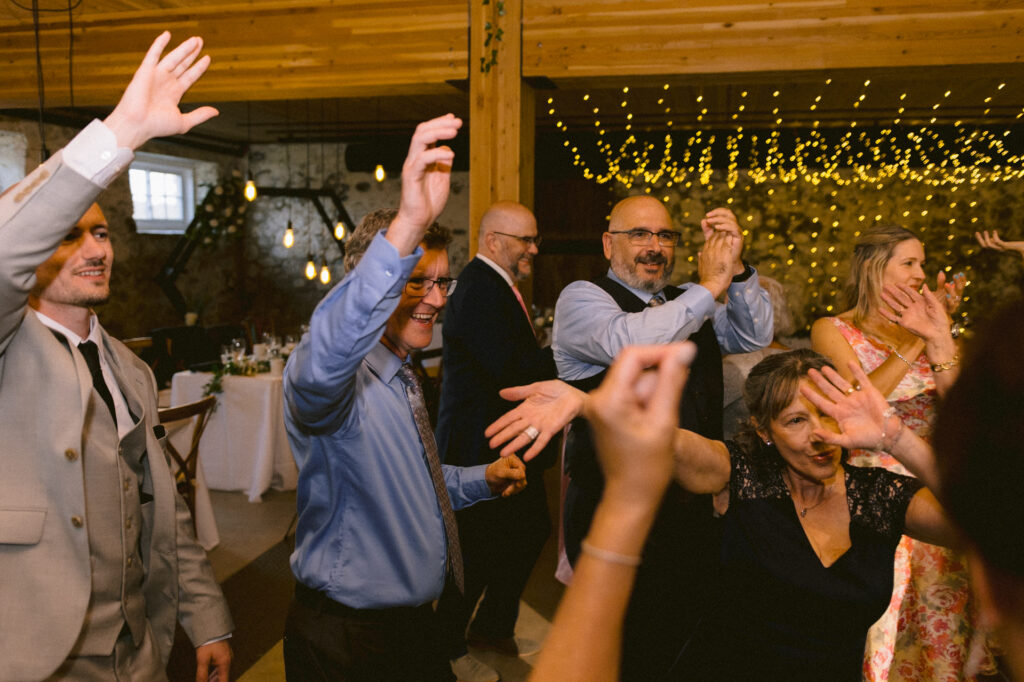 Guests raising their hands and dancing at a wedding.