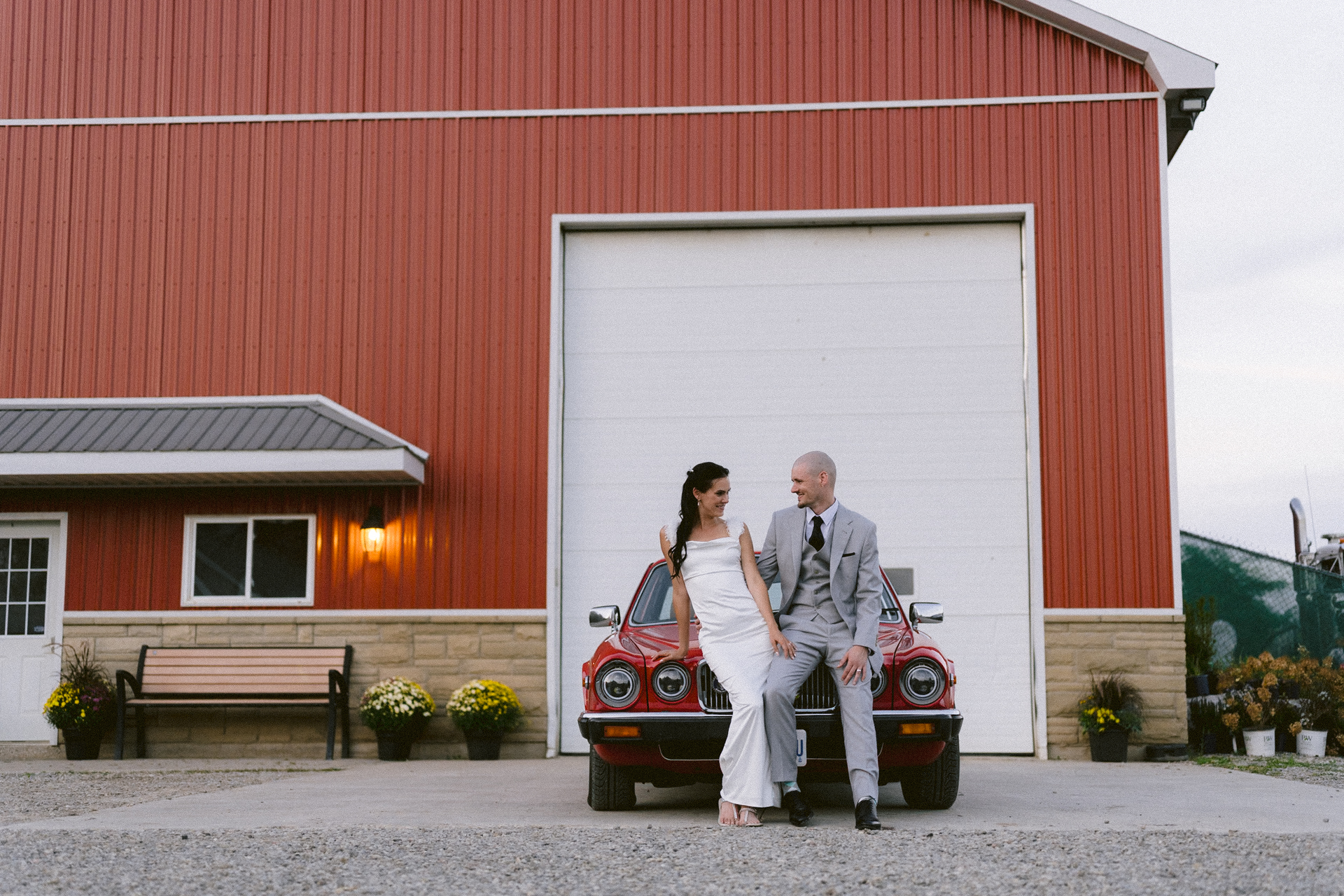 Newlyweds in front of a classic red car pose for their couple portrait in front of the Toronto wedding photographer.