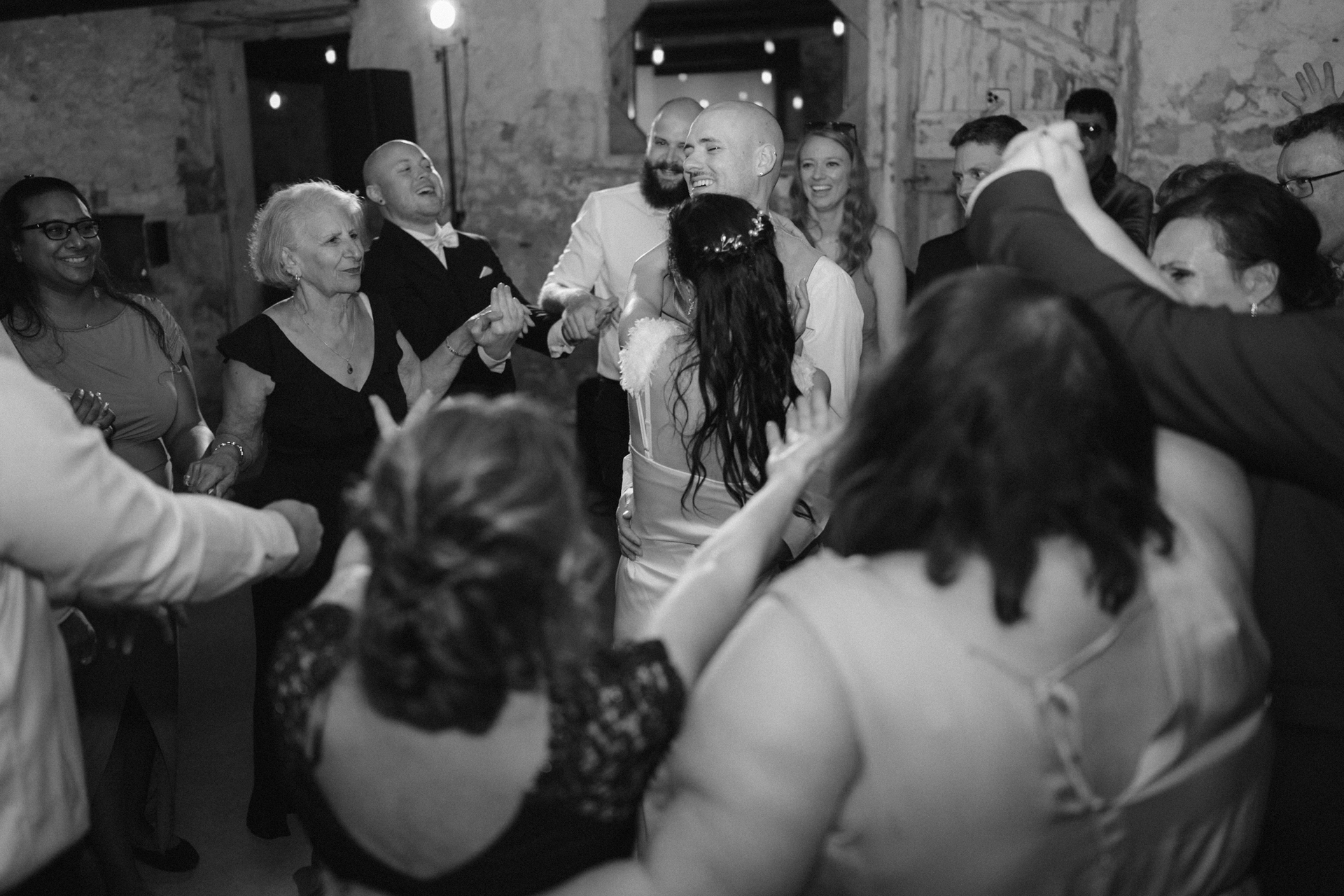 Bride and groom joyfully dancing with guests surround them at a wedding reception.