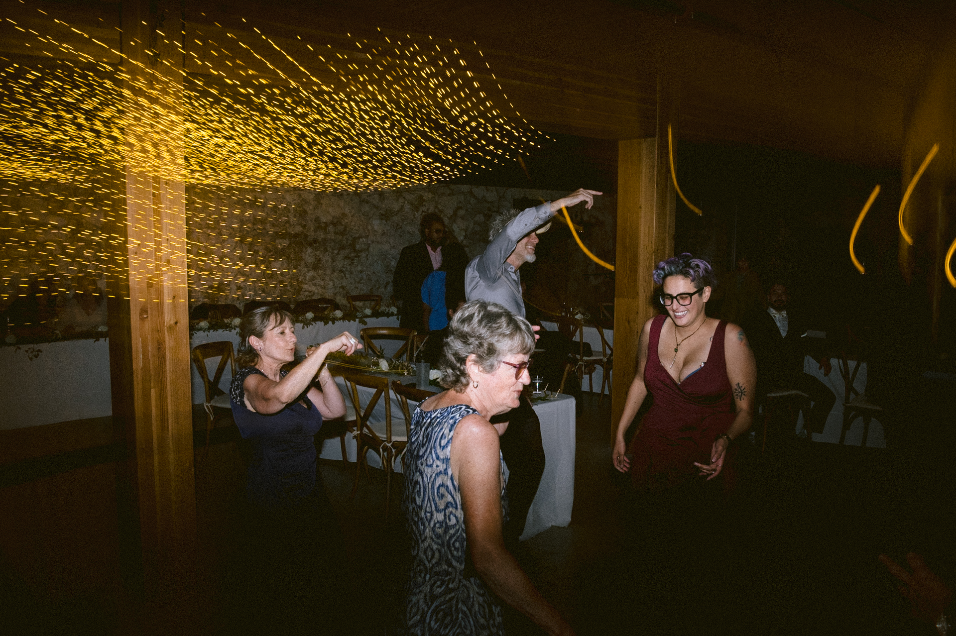 Guests dance joyfully at the dance floor with beautiful hanging light as a backdrop.