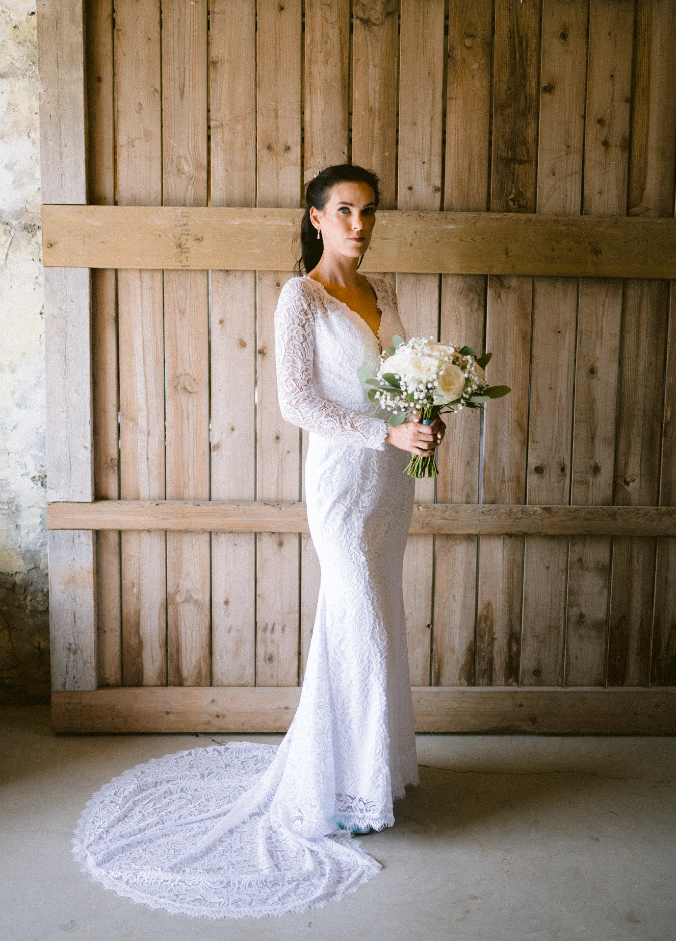 A bride in a lace wedding gown holding a bouquet.