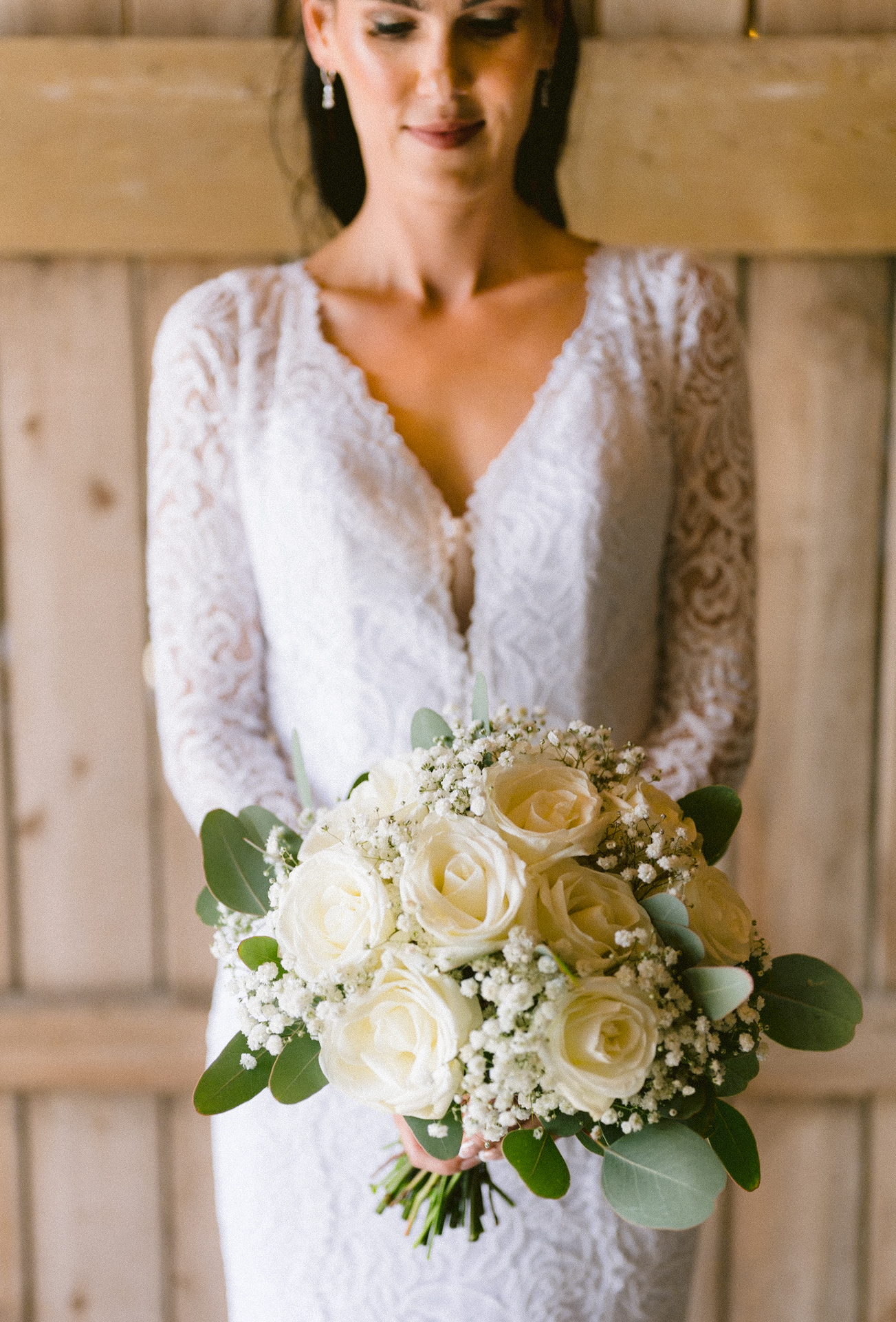 A bride in a lace wedding gown holding a bouquet and pose for her Toronto wedding photographer.