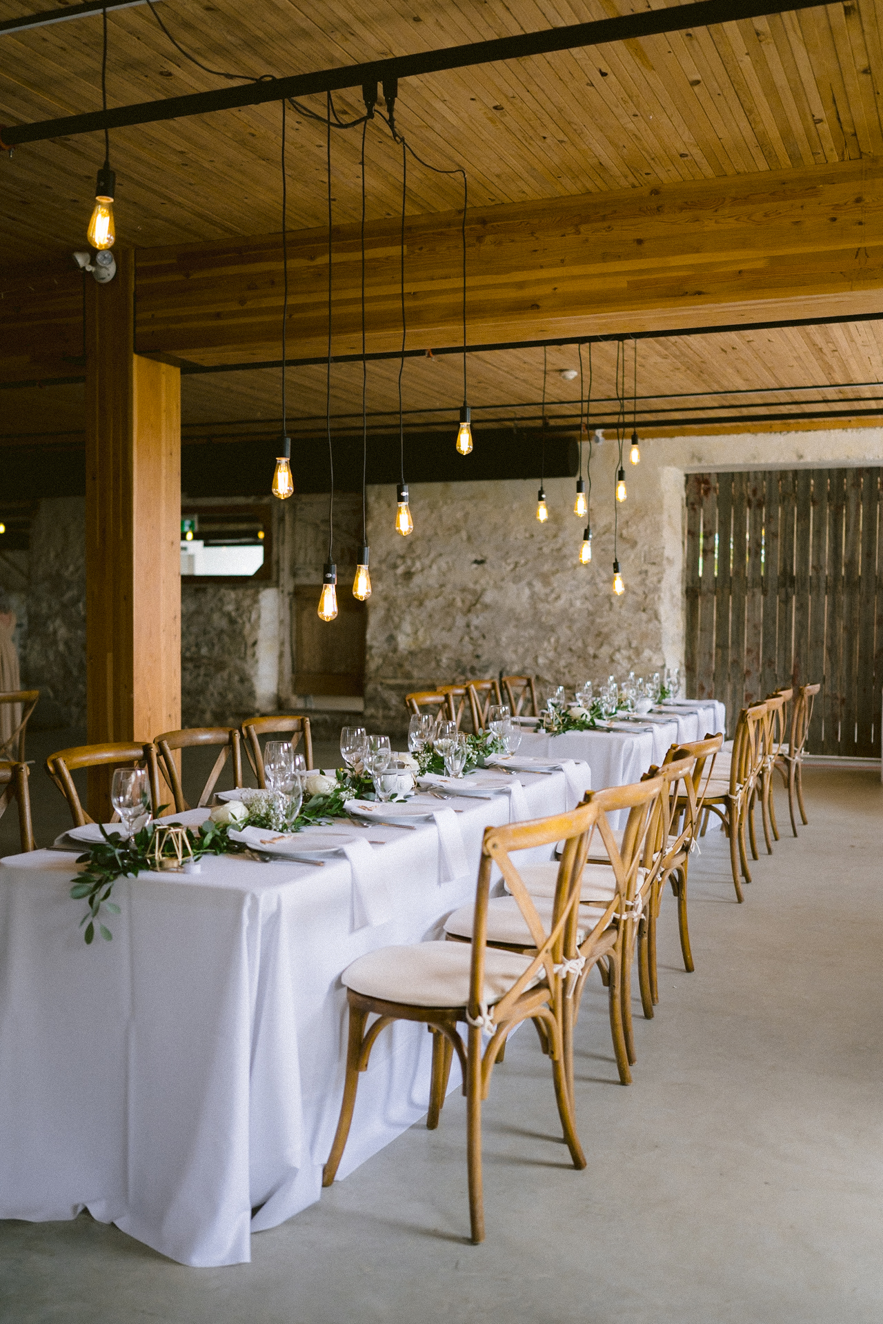An elegantly set banquet table with floral centerpieces and string lights at The Byre, Cambium Farms.