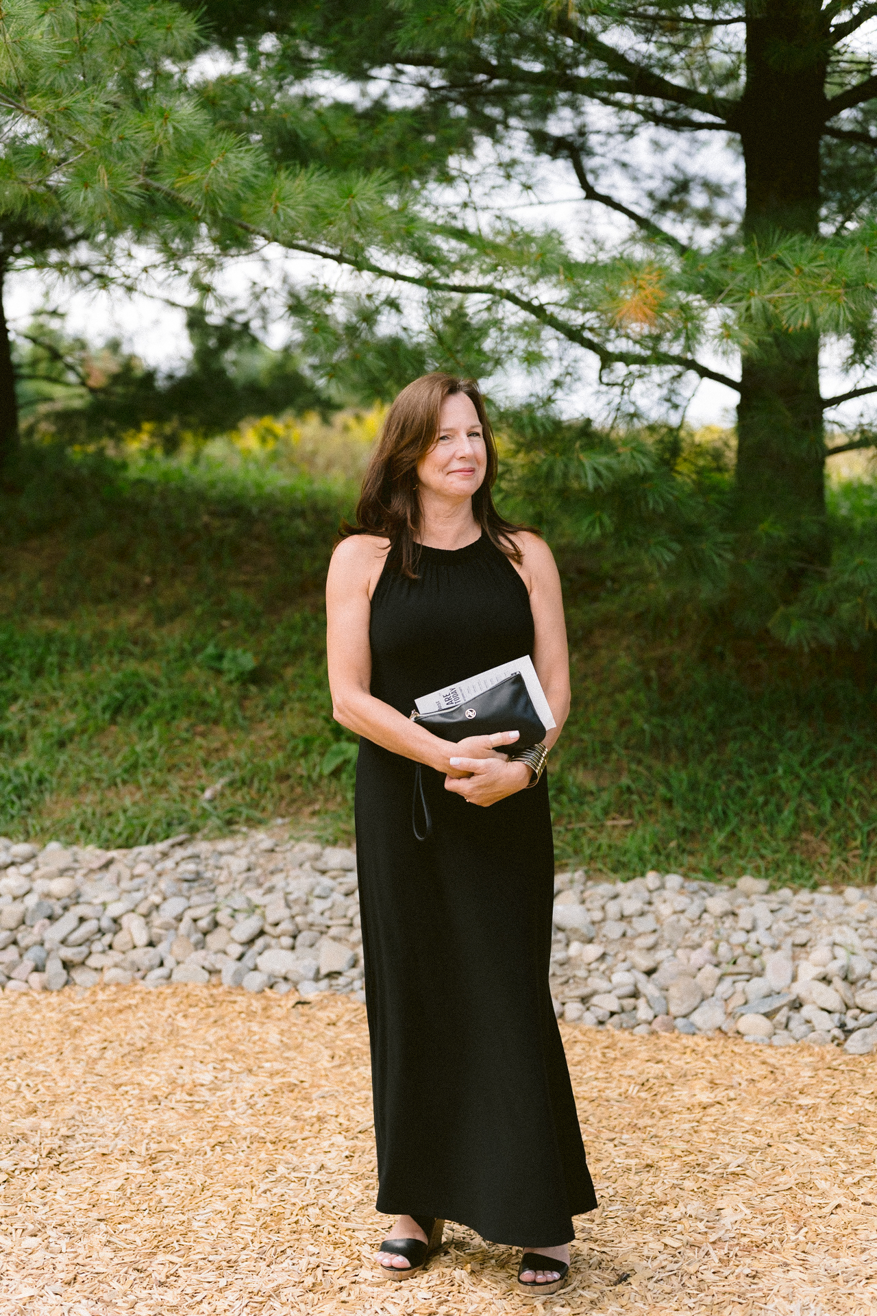 Stylish guest in black attire with purse, awaiting wedding ceremony.