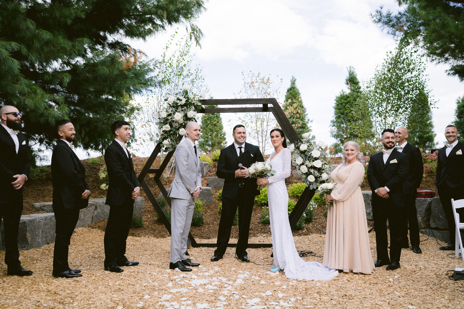 A wedding ceremony in progress with a bride and groom standing at the altar, surrounded by groomsmen and a bridesmaid