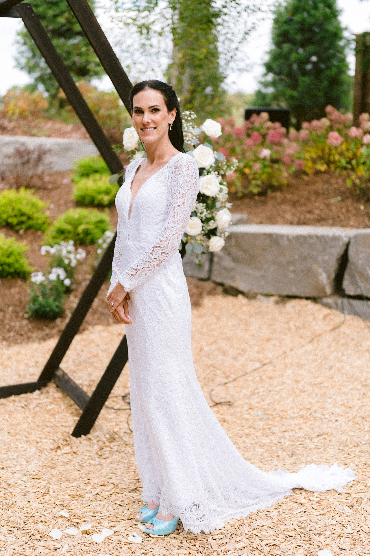 A bride in a long-sleeve lace wedding dress smiling at Cambium Farms outdoor wedding.