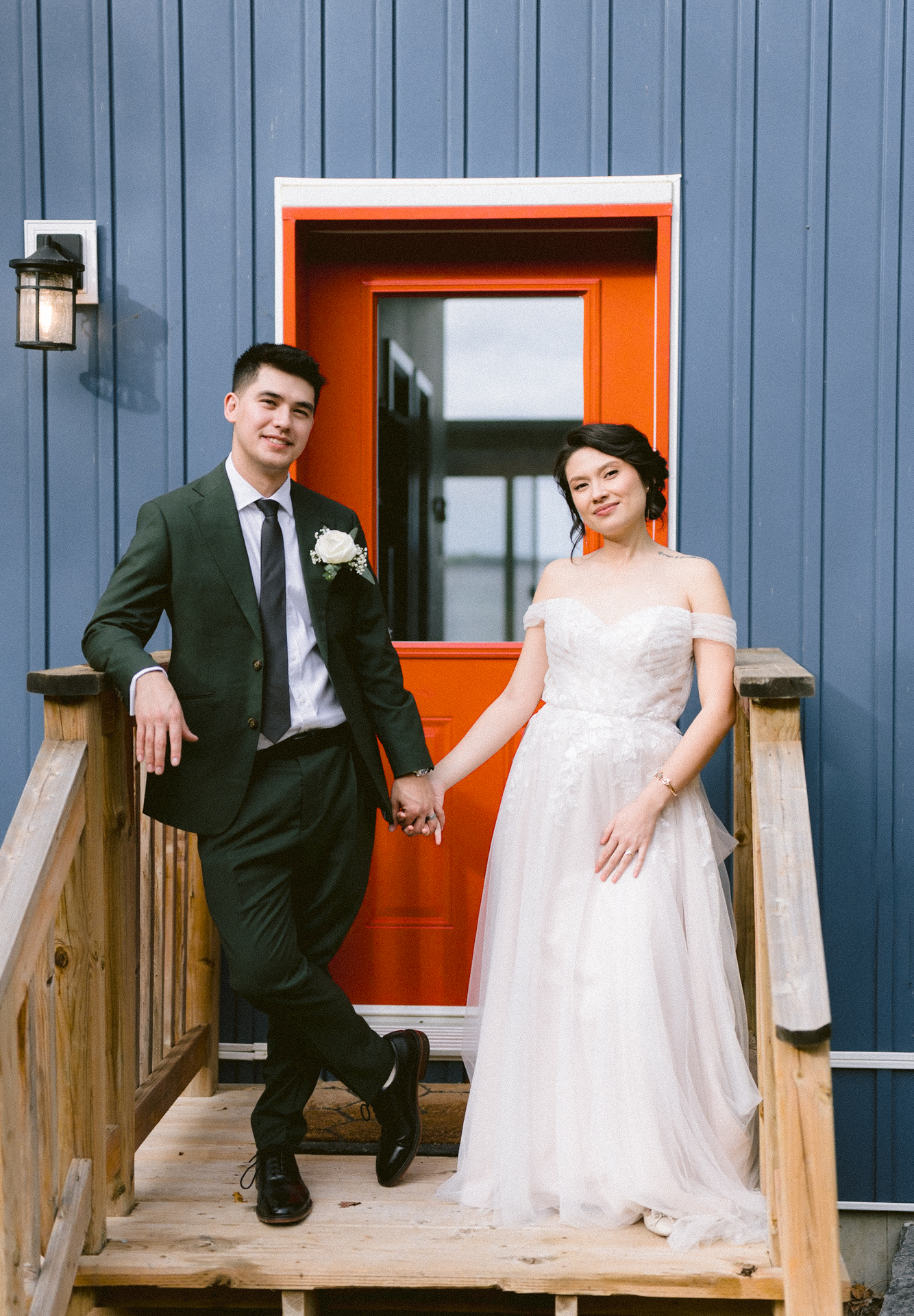 Newlyweds posing in front of a vibrant red door, embodying elegance and happiness