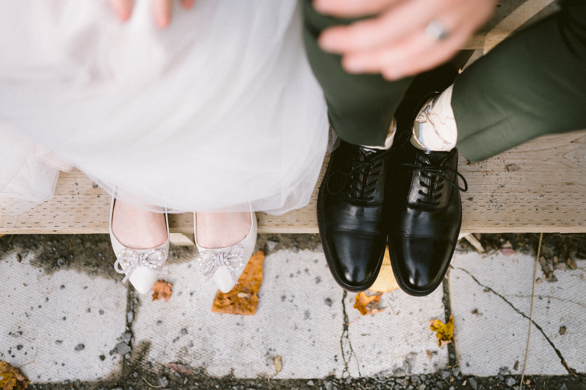 A bride and groom standing close together, showcasing their wedding attire and shoes.