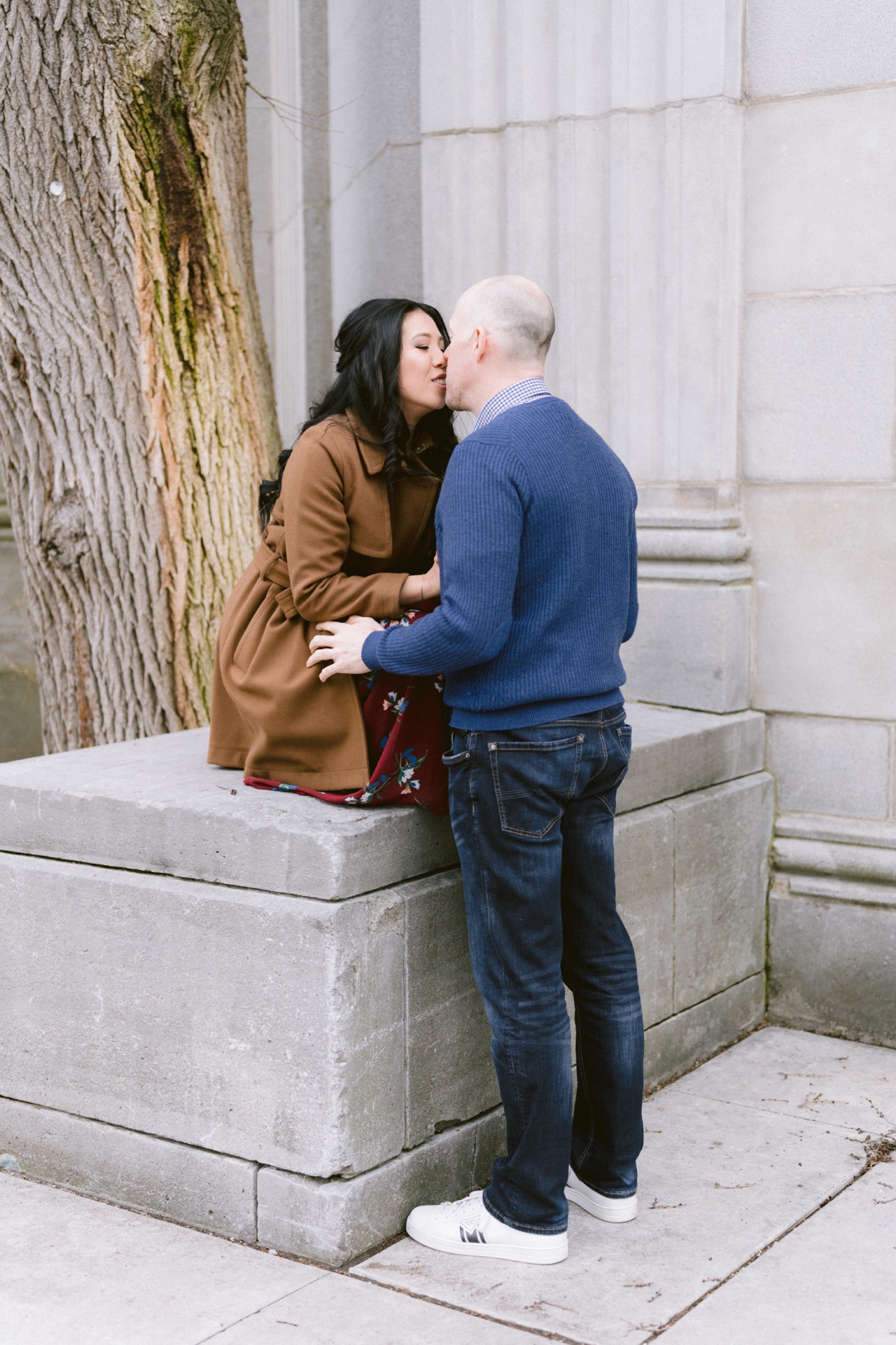 A couple sharing a romantic moment by a stone structure outdoors.