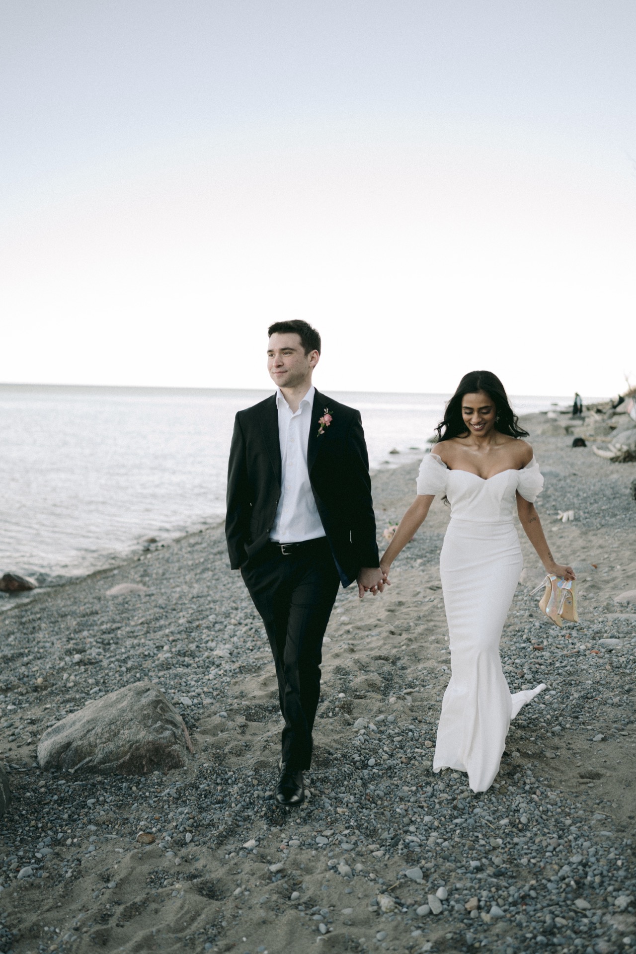 The newlywed enjoy the walk during golden hour after their wedding ceremony by Lake Ontario.
