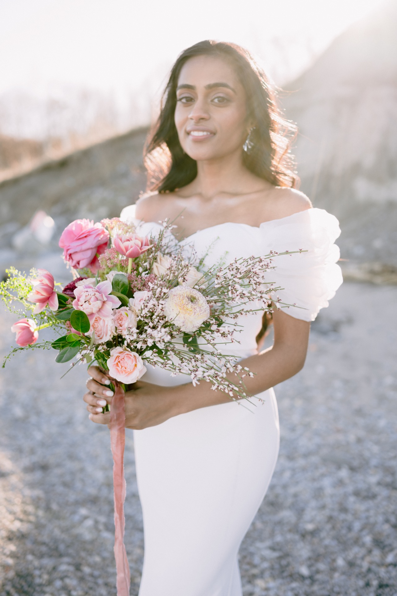 A bride holding a colourful bouquet and pose for her wedding photographer.
