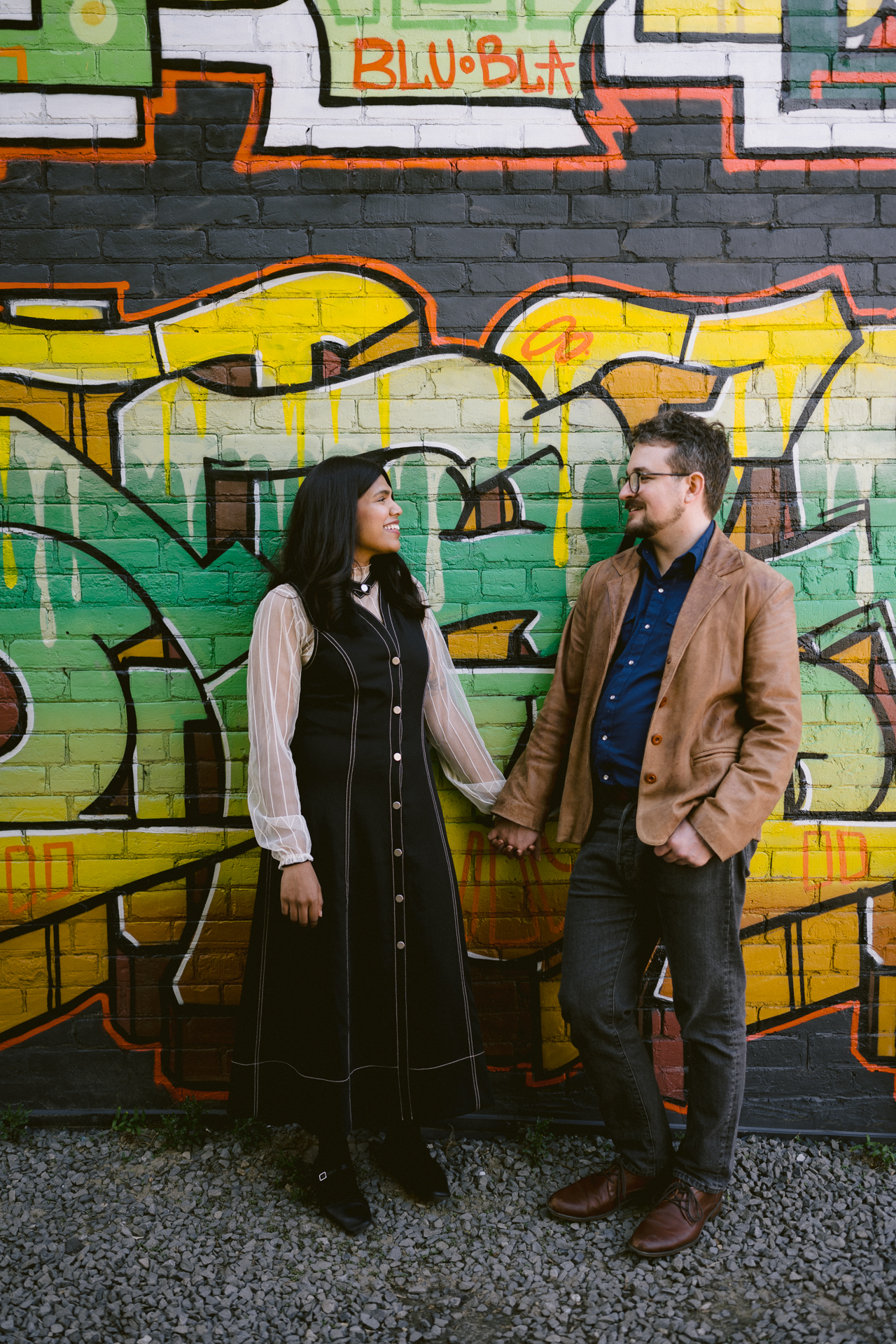 A romantic moments between a couple posing in front of a artistic murals at Gerrard Street during their engagement photoshoot.